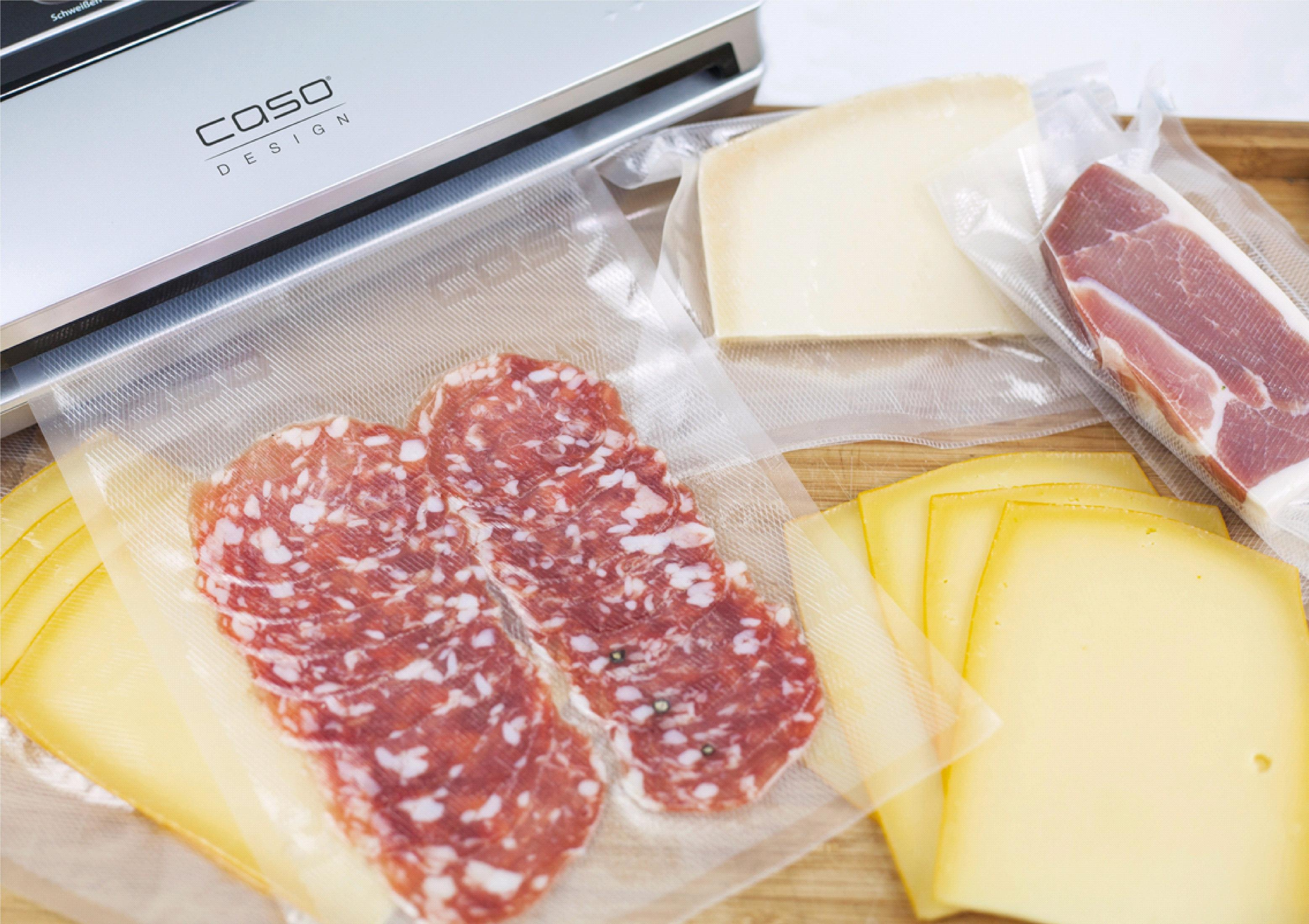 Sigillatrice sottovuoto con salame a fette, formaggio e prosciutto, confezionati in plastica trasparente.