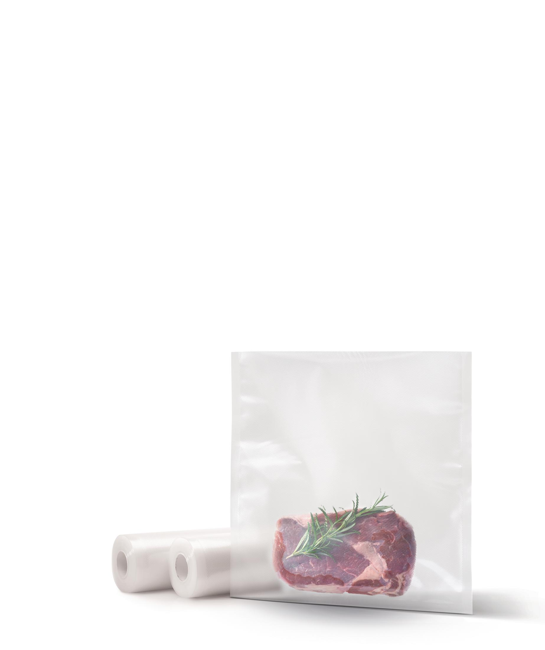 Rohes Fleisch in einem Vakuumbeutel mit Rosmarin. Daneben zwei Rollen Plastikfolie.