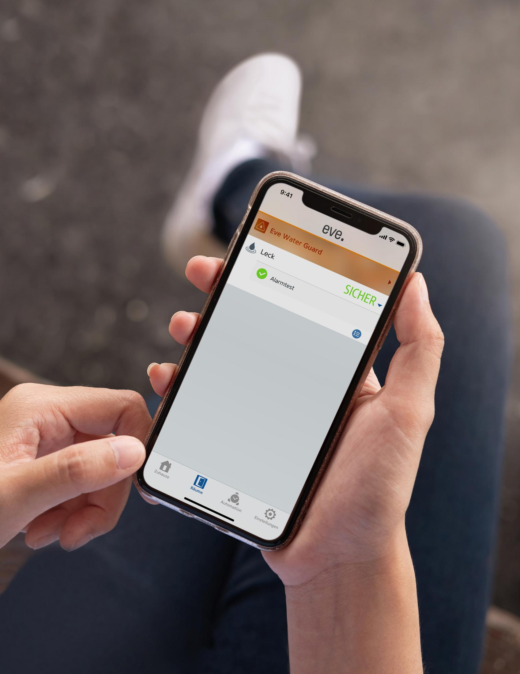 Eine Person, die ein Smartphone mit einer Benutzeroberfläche einer Heimsicherheits-App hält.