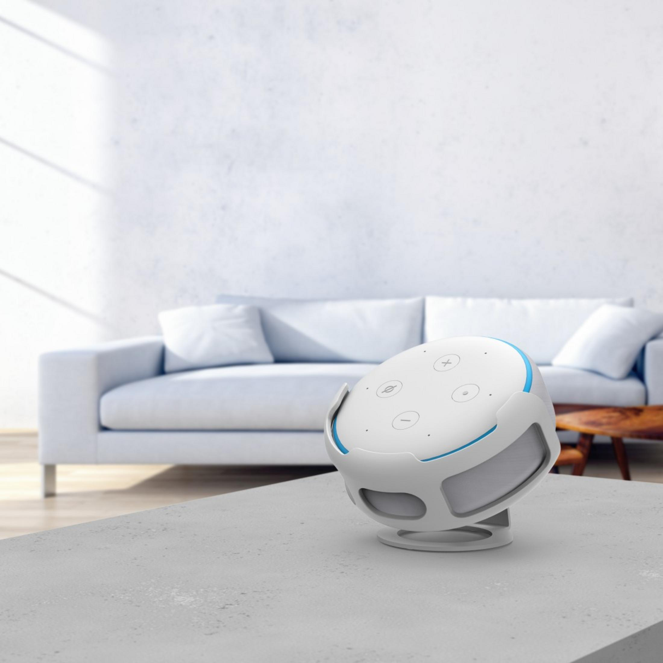 Weiß-blauer Smart Speaker auf einem Tisch. Eine weiße Couch im Hintergrund.