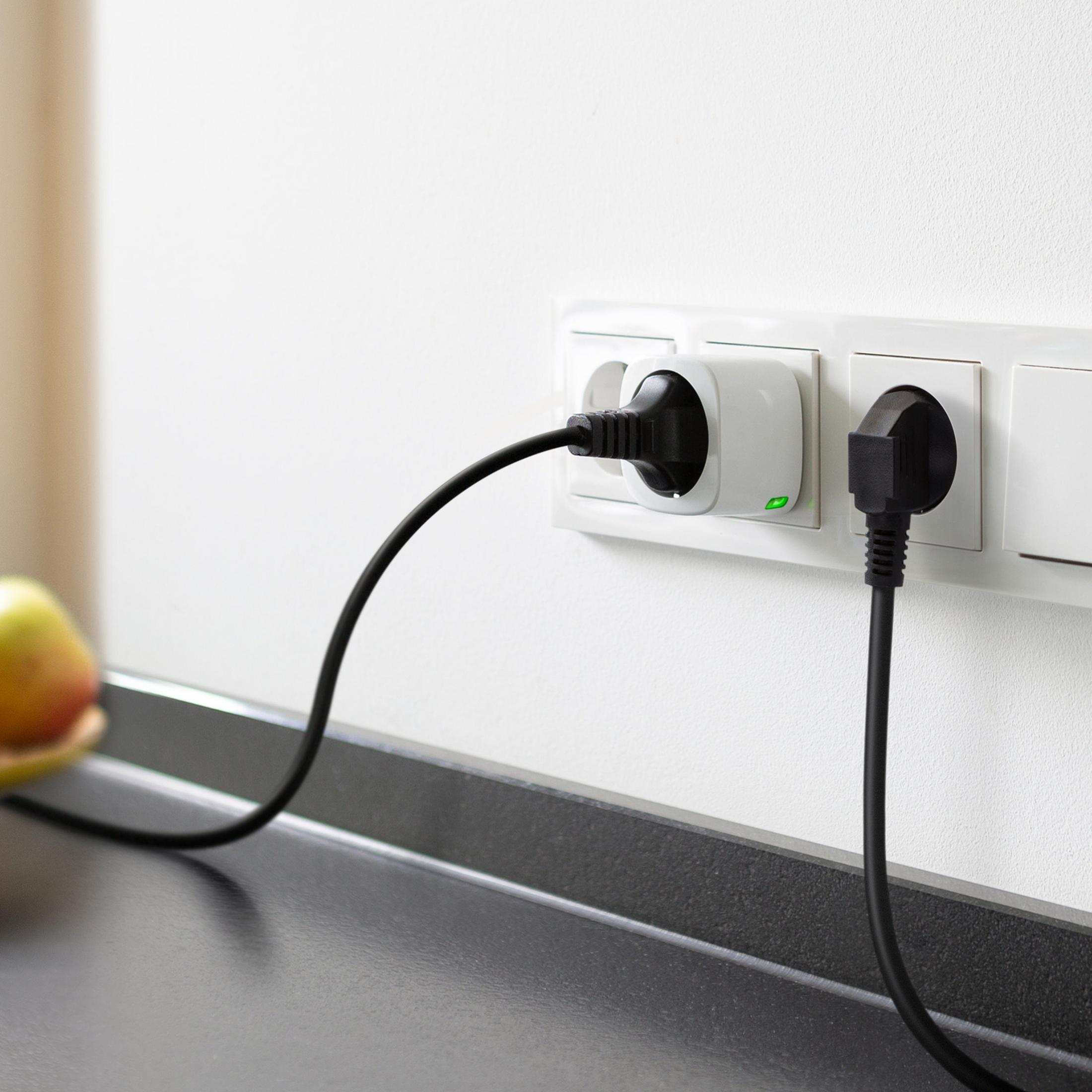Zwei Stecker in einer weißen Wand. Ein schwarzes Kabel angeschlossen. Ein grünes Licht am Stecker.