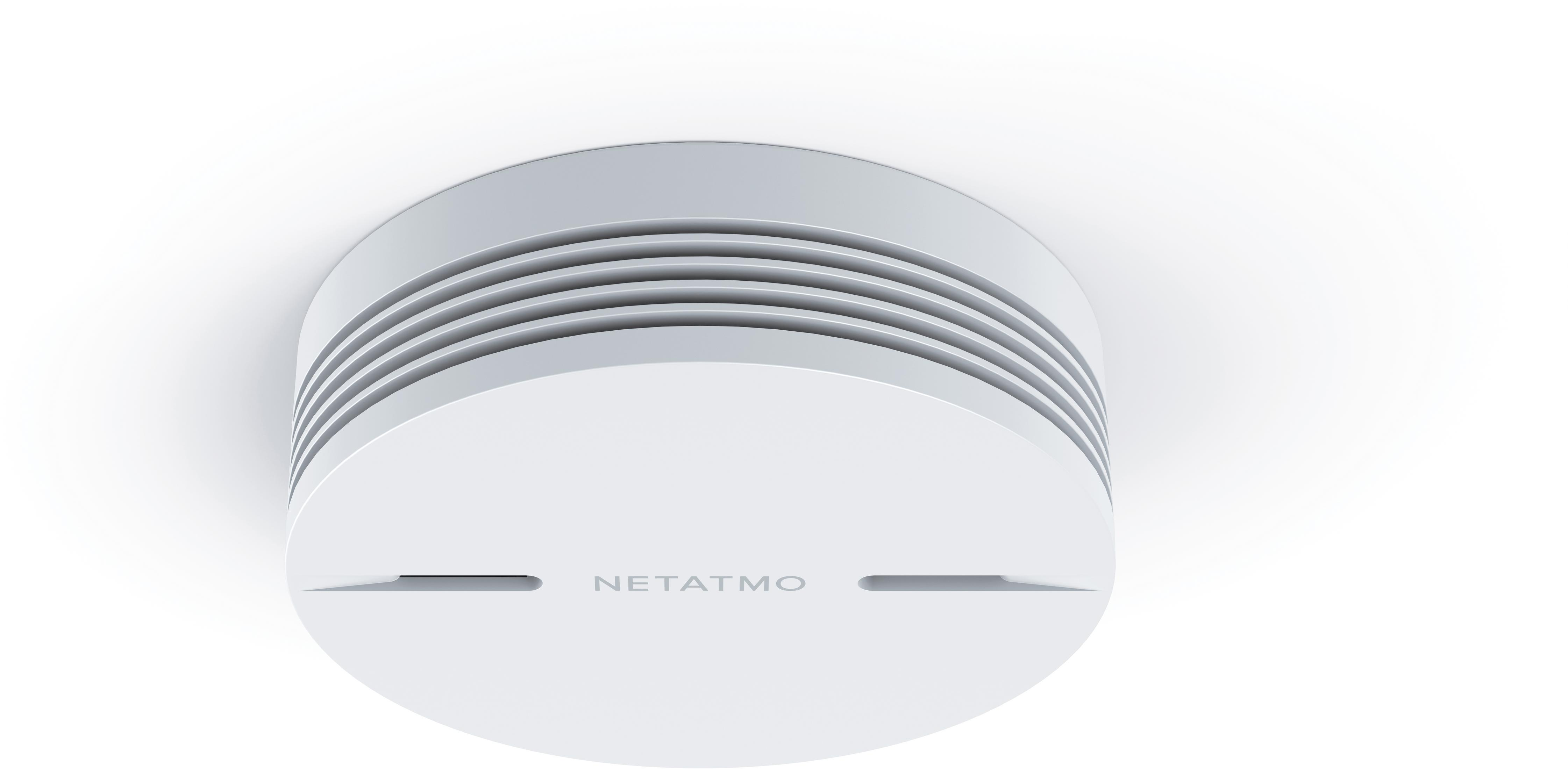 Biały czujnik dymu Netatmo, okrągły kształt, zamontowany na białym suficie, zbliżenie.