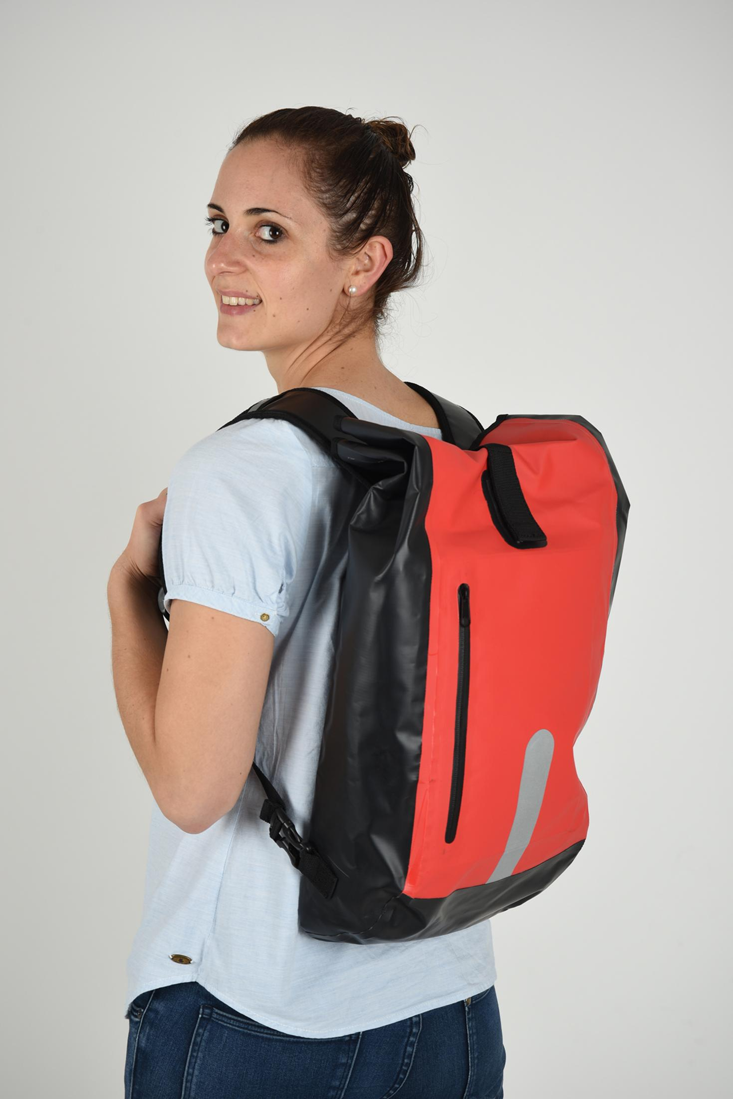 Eine lächelnde Frau, die einen Rucksack trägt. Der Rucksack ist rot und schwarz.