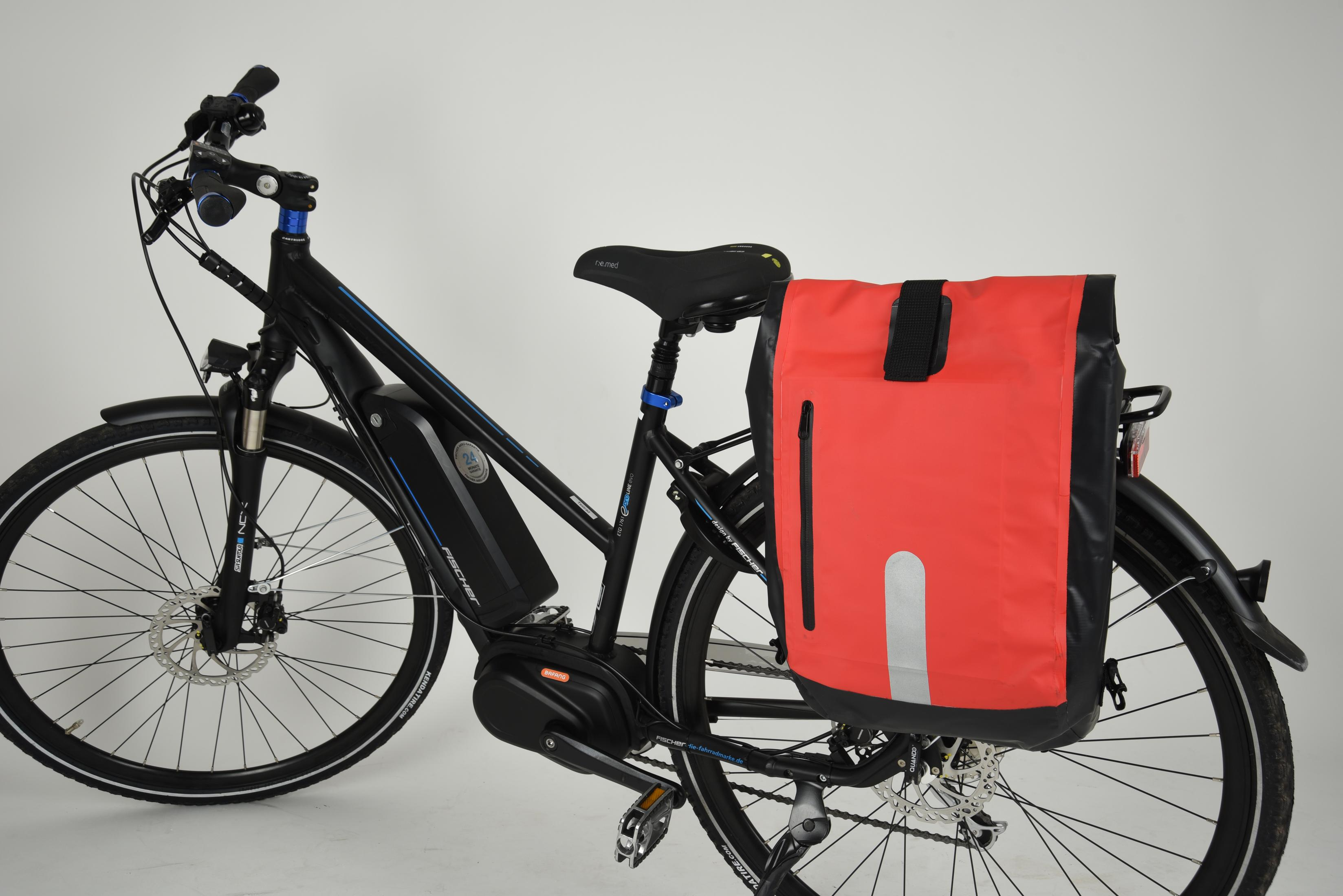 Schwarzes und blaues Elektrofahrrad mit roter Packtasche. Weißer Hintergrund.