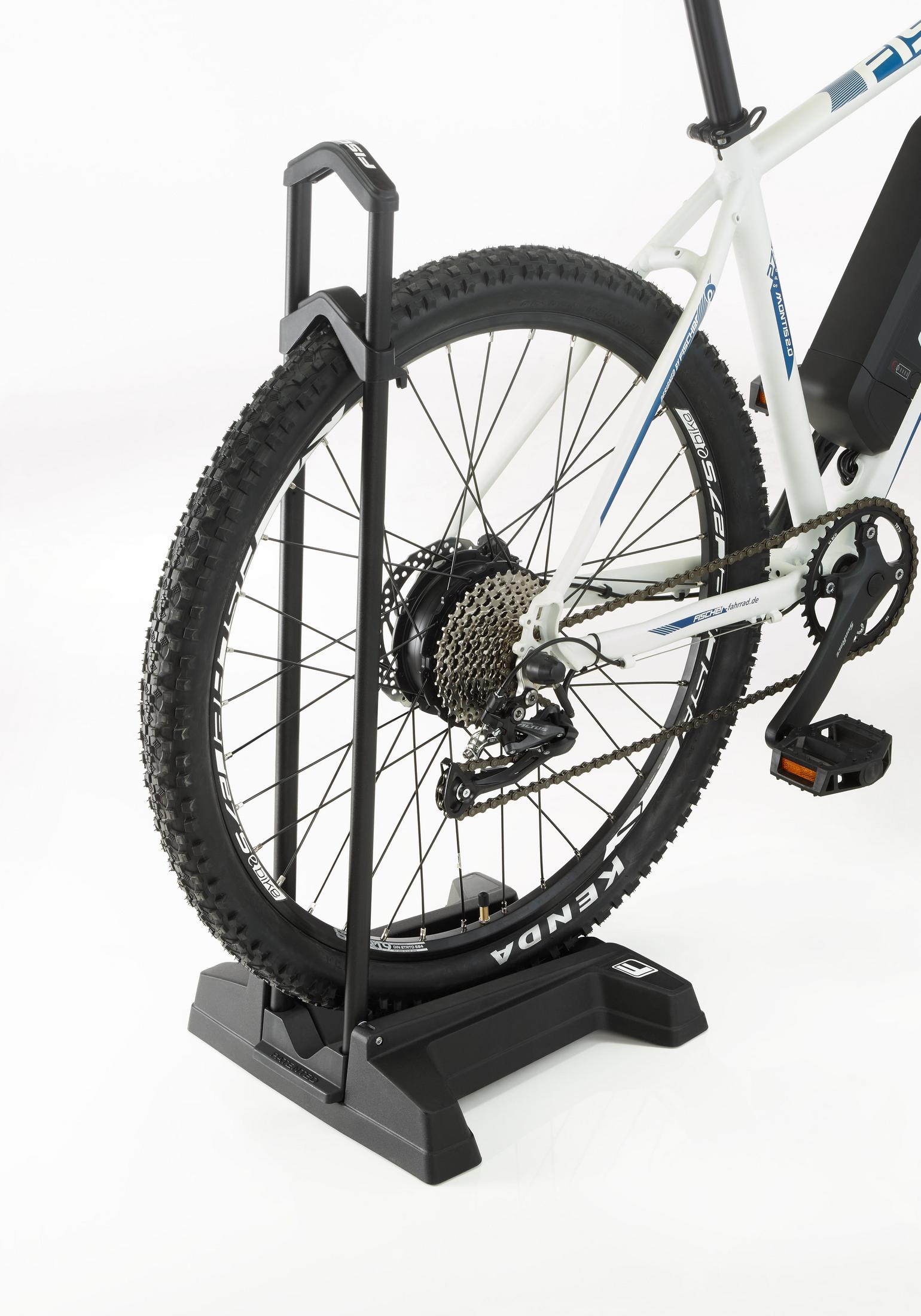 Ein Fahrradrad, das von einem schwarzen Ständer getragen wird. Das Fahrrad ist weiß und schwarz.
