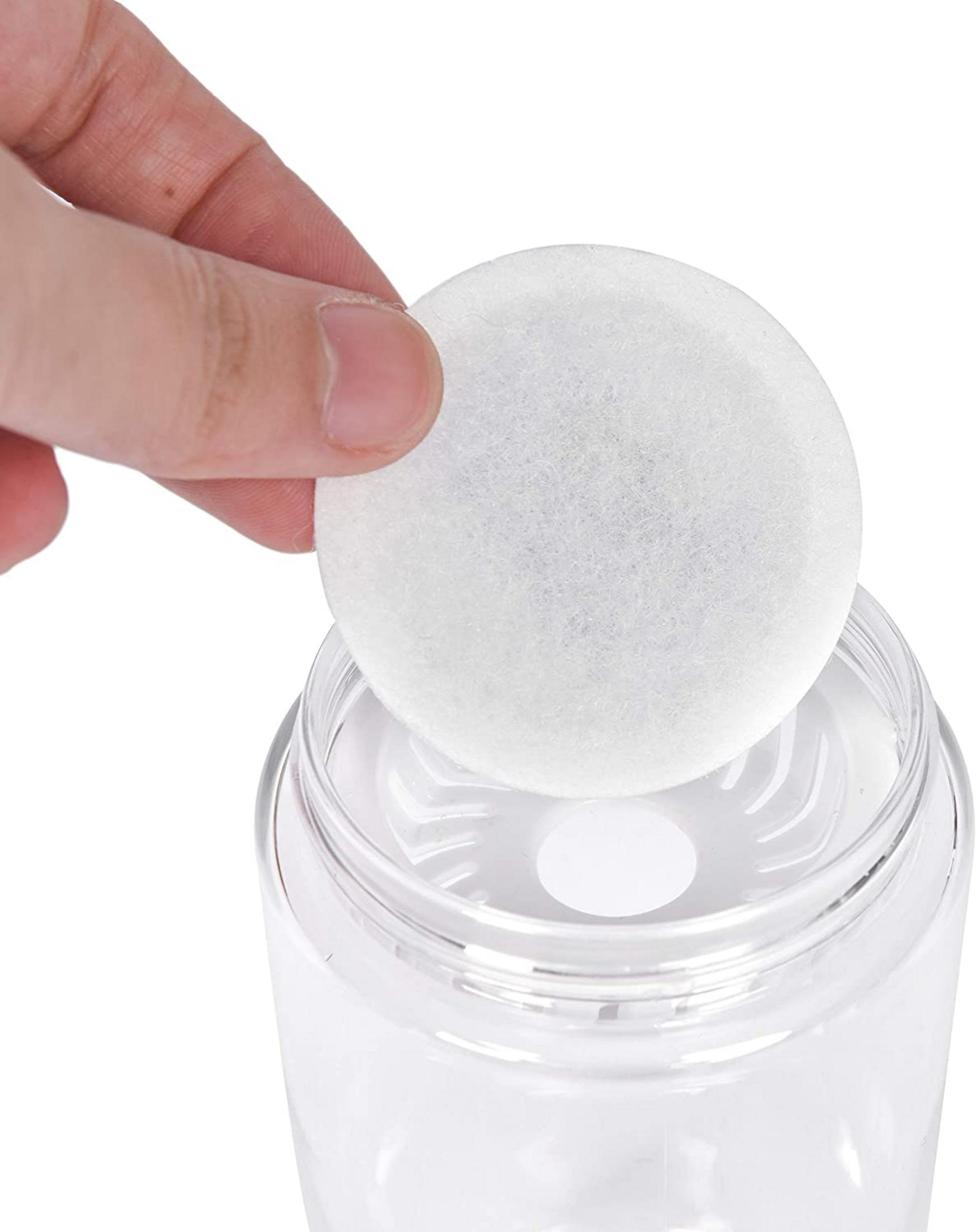 Mano che tiene un filtro bianco rotondo sopra una bottiglia d'acqua trasparente. Bottiglia di plastica trasparente.