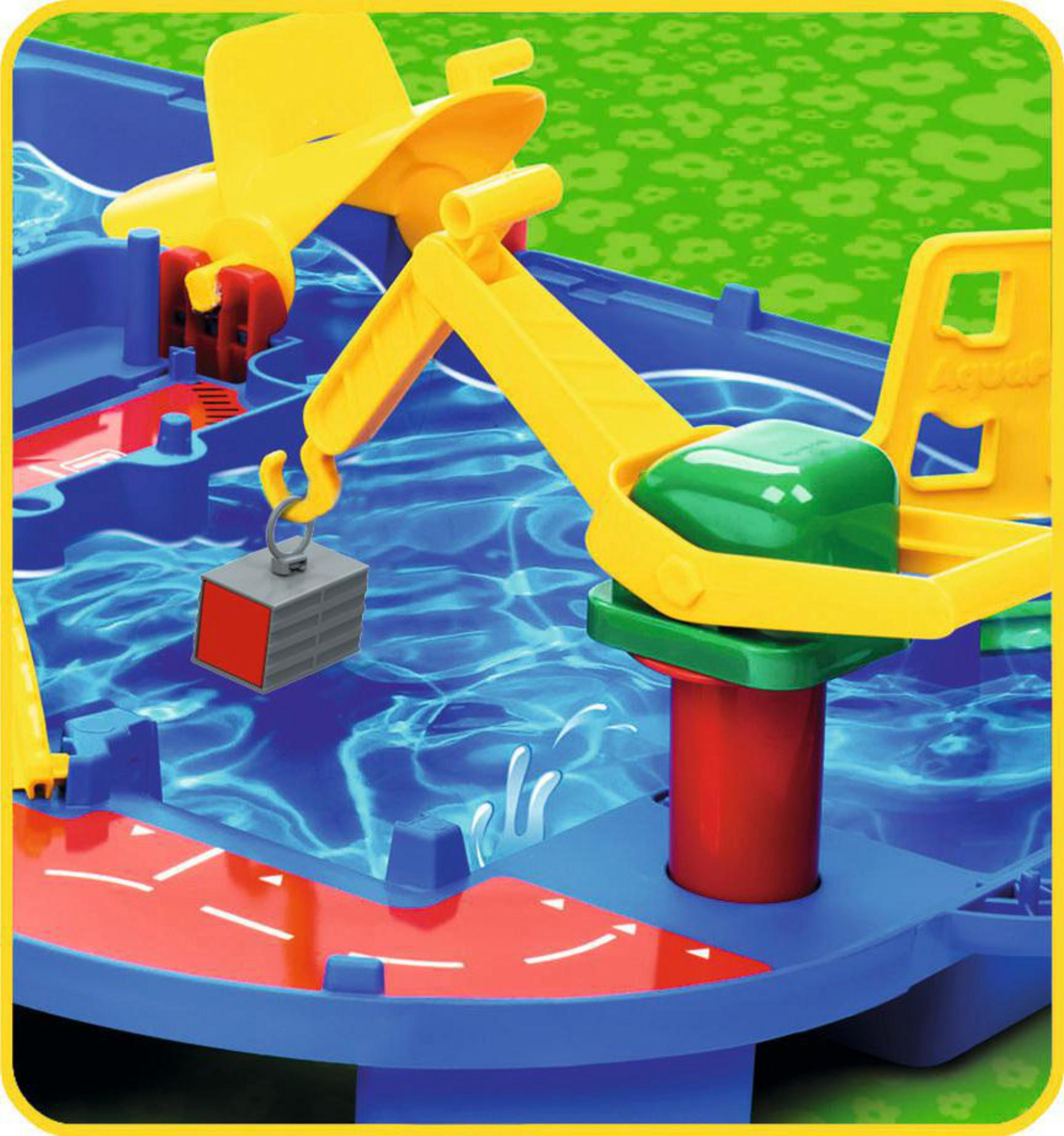 Un juguete de grúa amarilla levantando un bloque gris en un juego de agua azul.