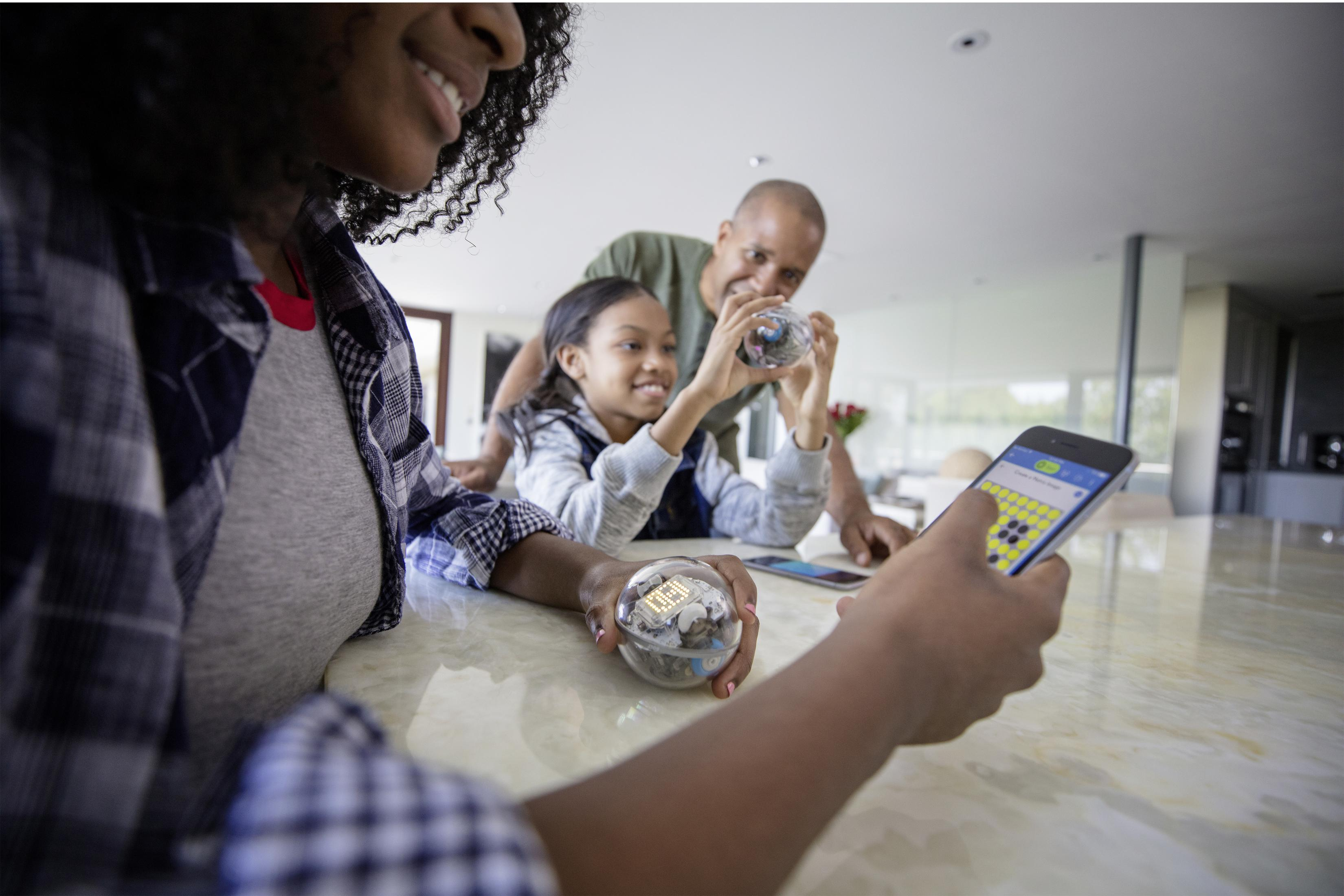 Famiglia gioca con due robot Sphero e un telefono.