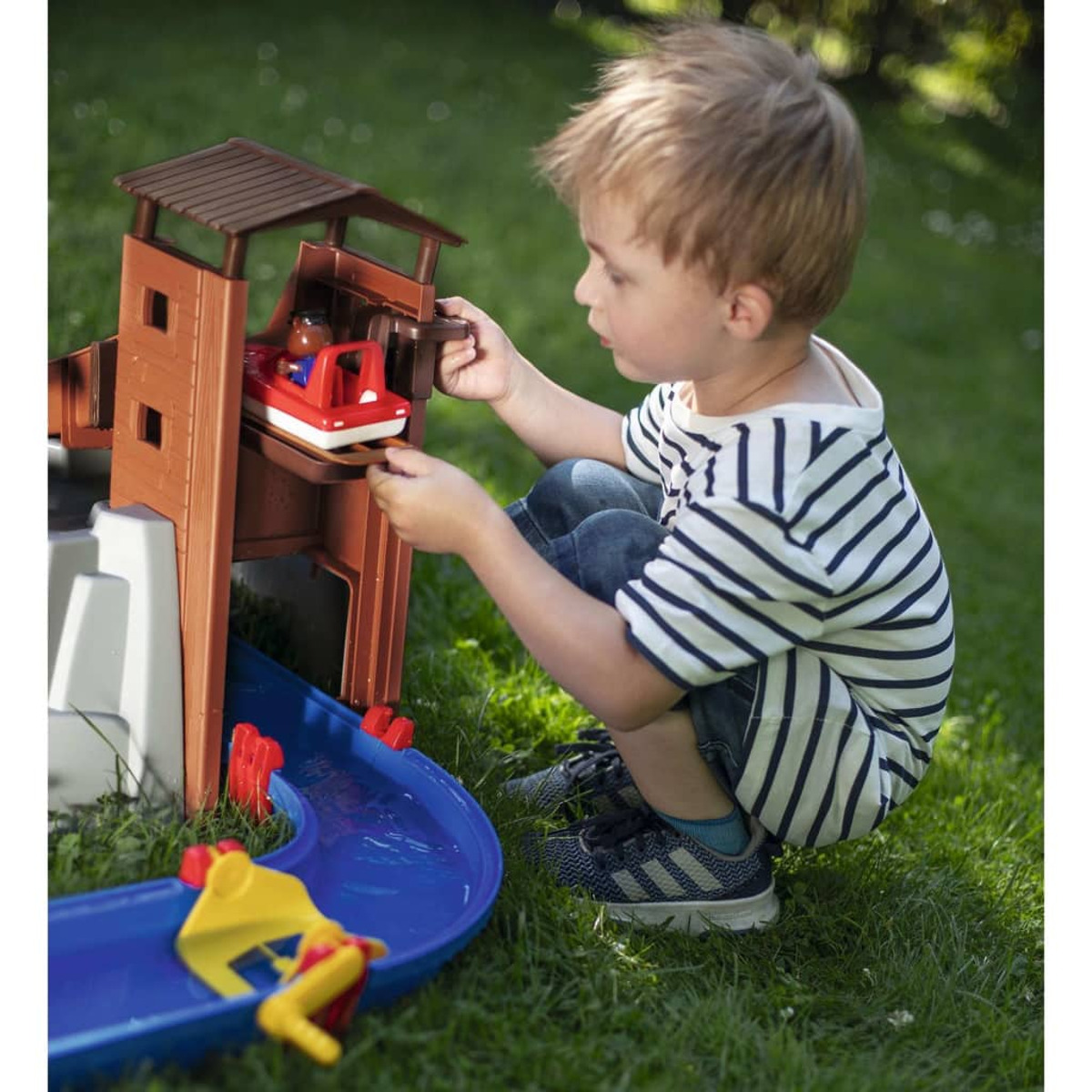 Junge spielt mit einem Spielzeug-Zugset. Das Set ist braun und blau.