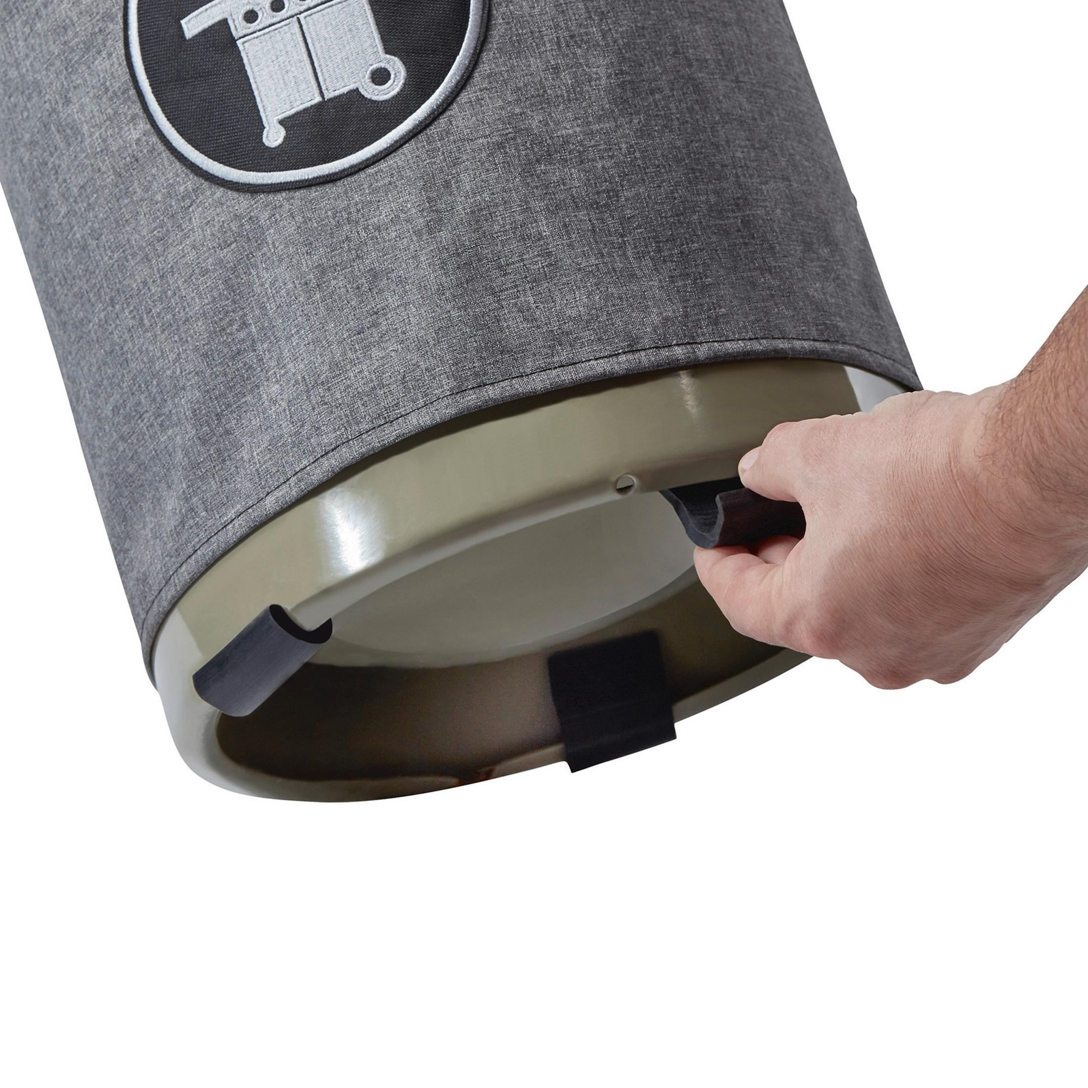 Eine Hand hält einen schwarzen Griff an einem grauen, kreisförmigen Wäschekorb mit Logo.