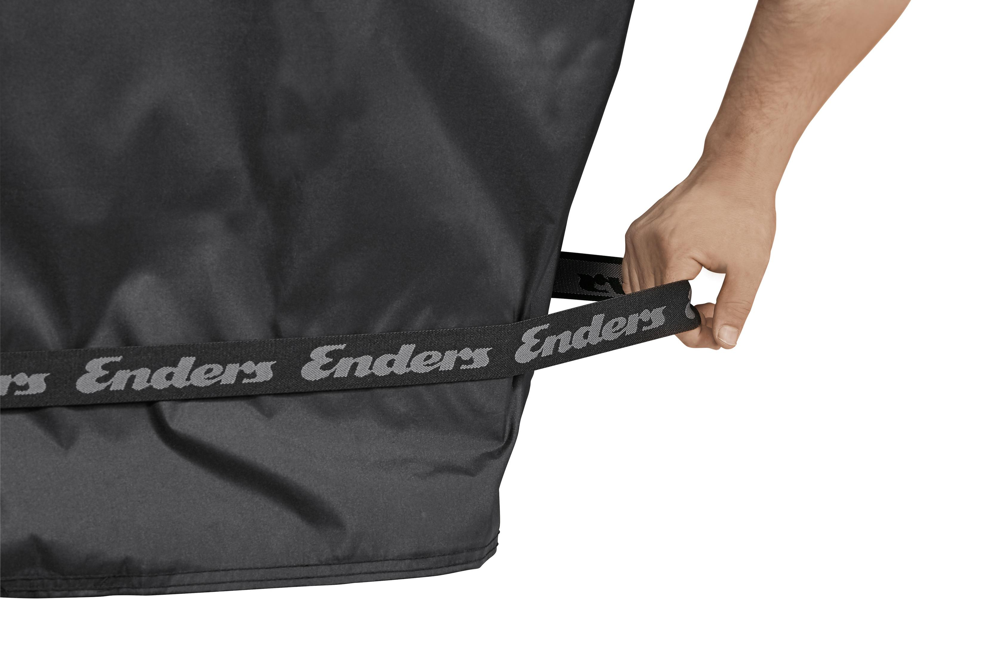 Eine Hand hält eine schwarze Abdeckung mit dem Aufdruck 'Enders' auf einem grauen Band. Die Abdeckung bedeckt ein Objekt.