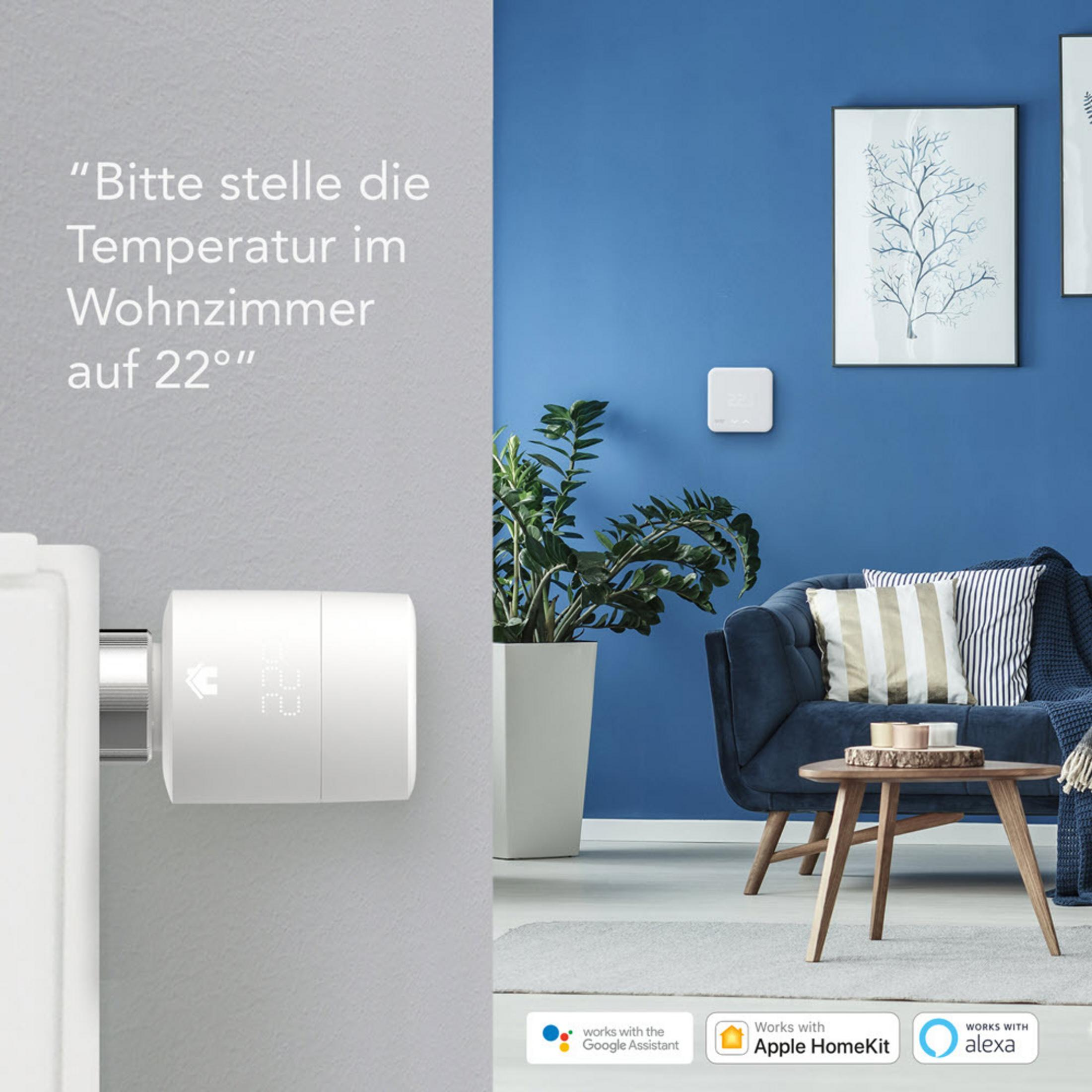 Een moderne woonkamer met een slimme thermostaat aan de muur, een blauwe bank en een plant.