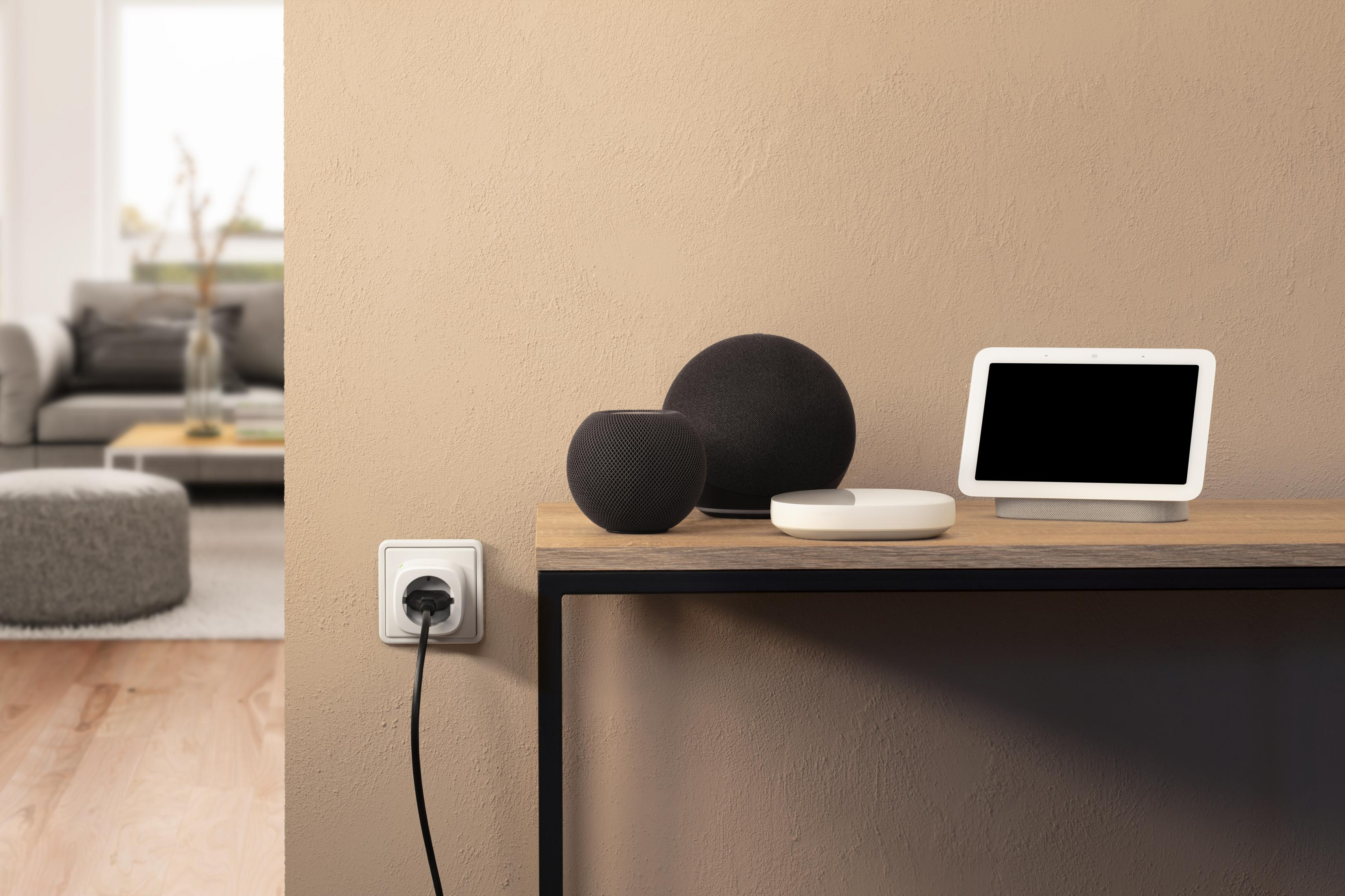 Wohndeko: Lautsprecher und Smart Display auf dem Tisch, Wandsteckdose. Beige Wand, Holzboden.