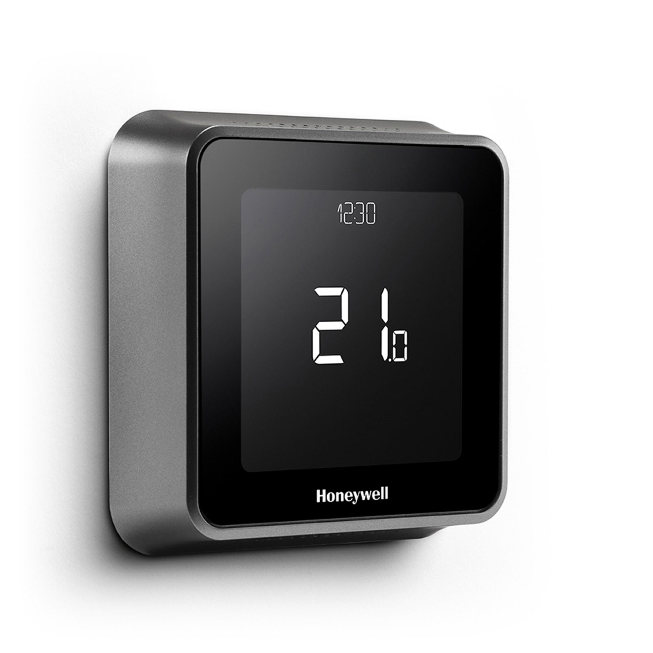 Ein grauer Honeywell-Thermostat an einer weißen Wand, der Zeit und Temperatur anzeigt. Es hat einen schwarzen Bildschirm.