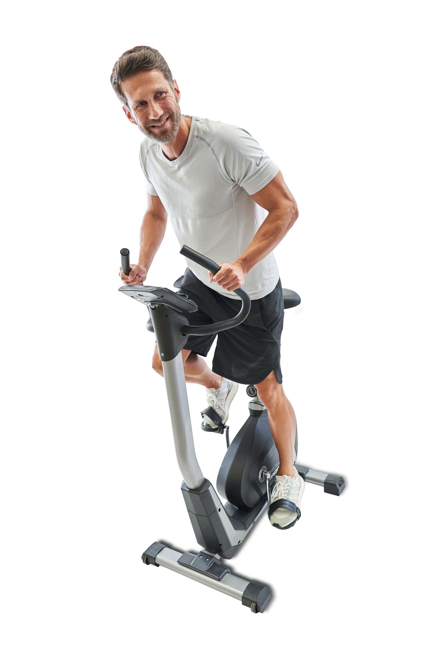 Man op hometrainer lachend, omhoog kijkend. Witte achtergrond.