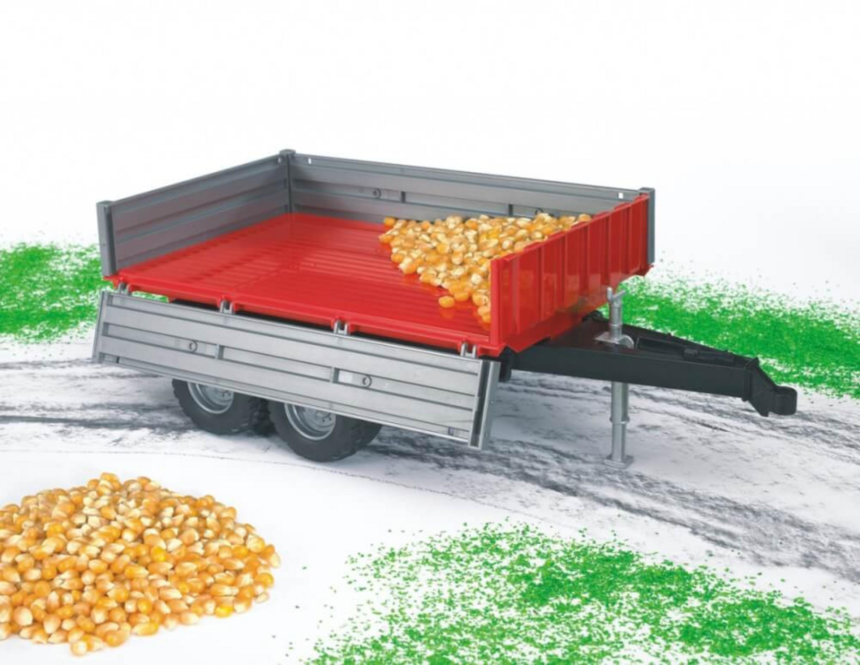 Zabawkowa przyczepa wypełniona kukurydzą, na białej powierzchni, z trawą.