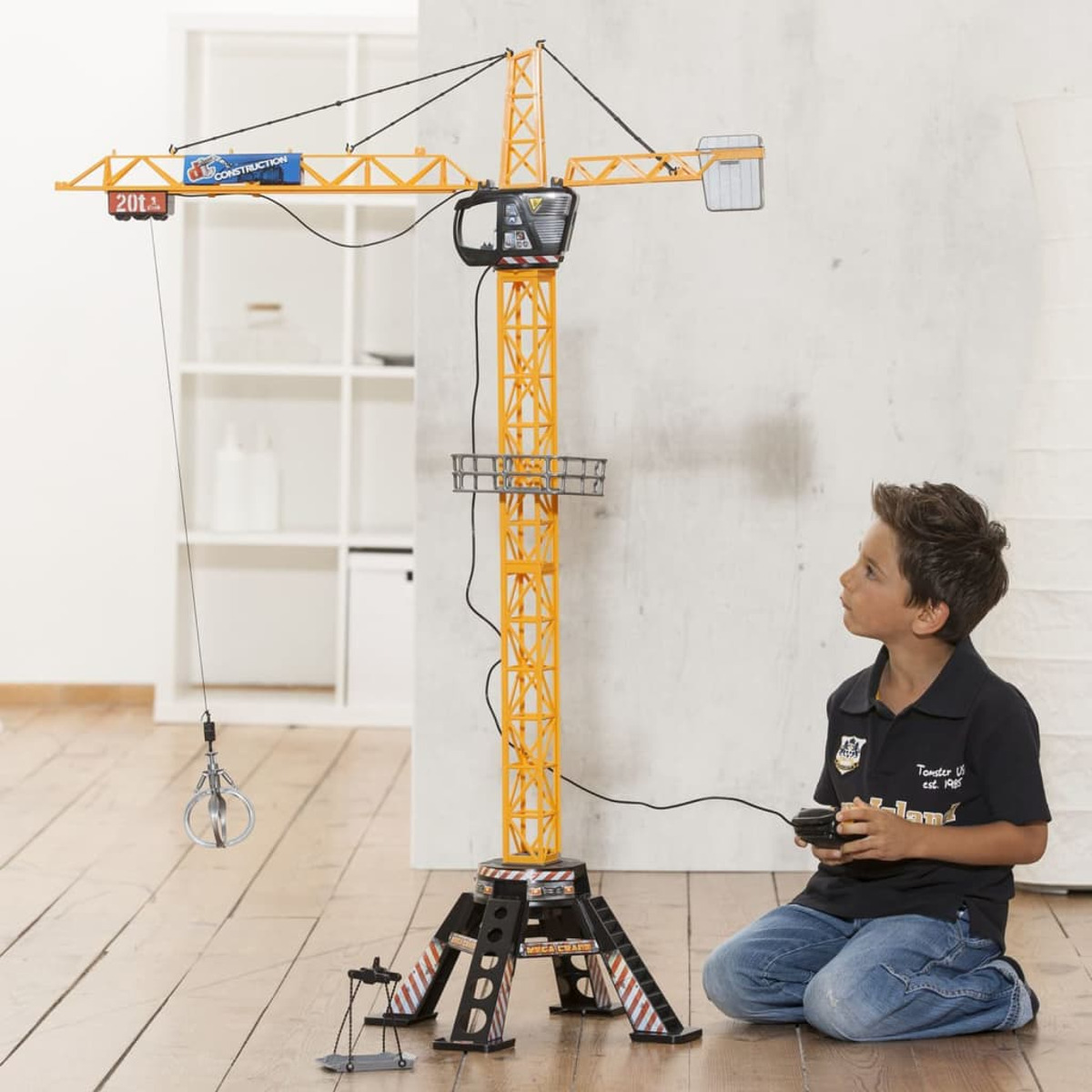 Junge spielt mit einem Spielzeug-Baukran. Der Kran ist gelb und orange.