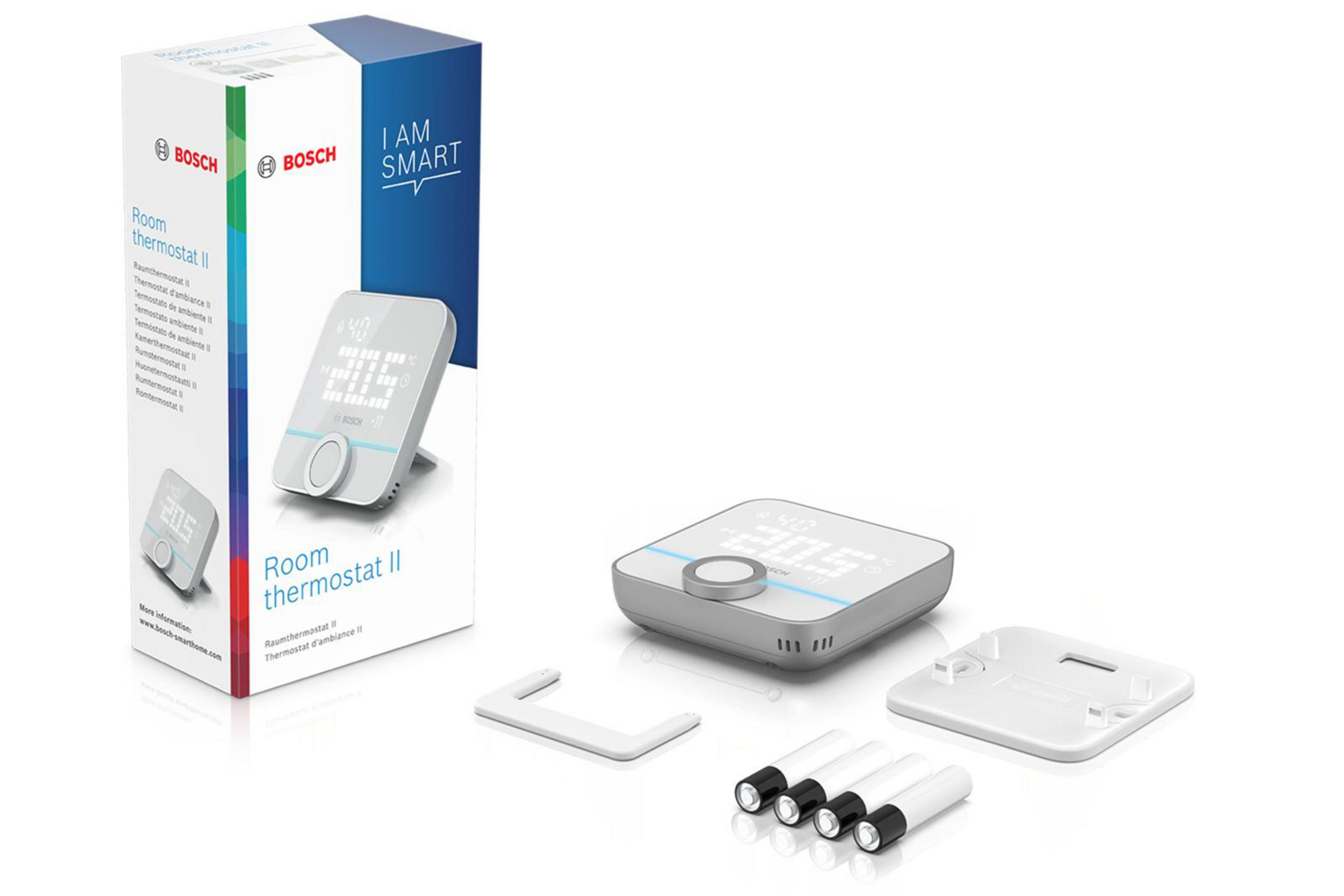 Ein Bosch Raumthermostat II, Karton und Zubehör liegen auf weißem Untergrund.