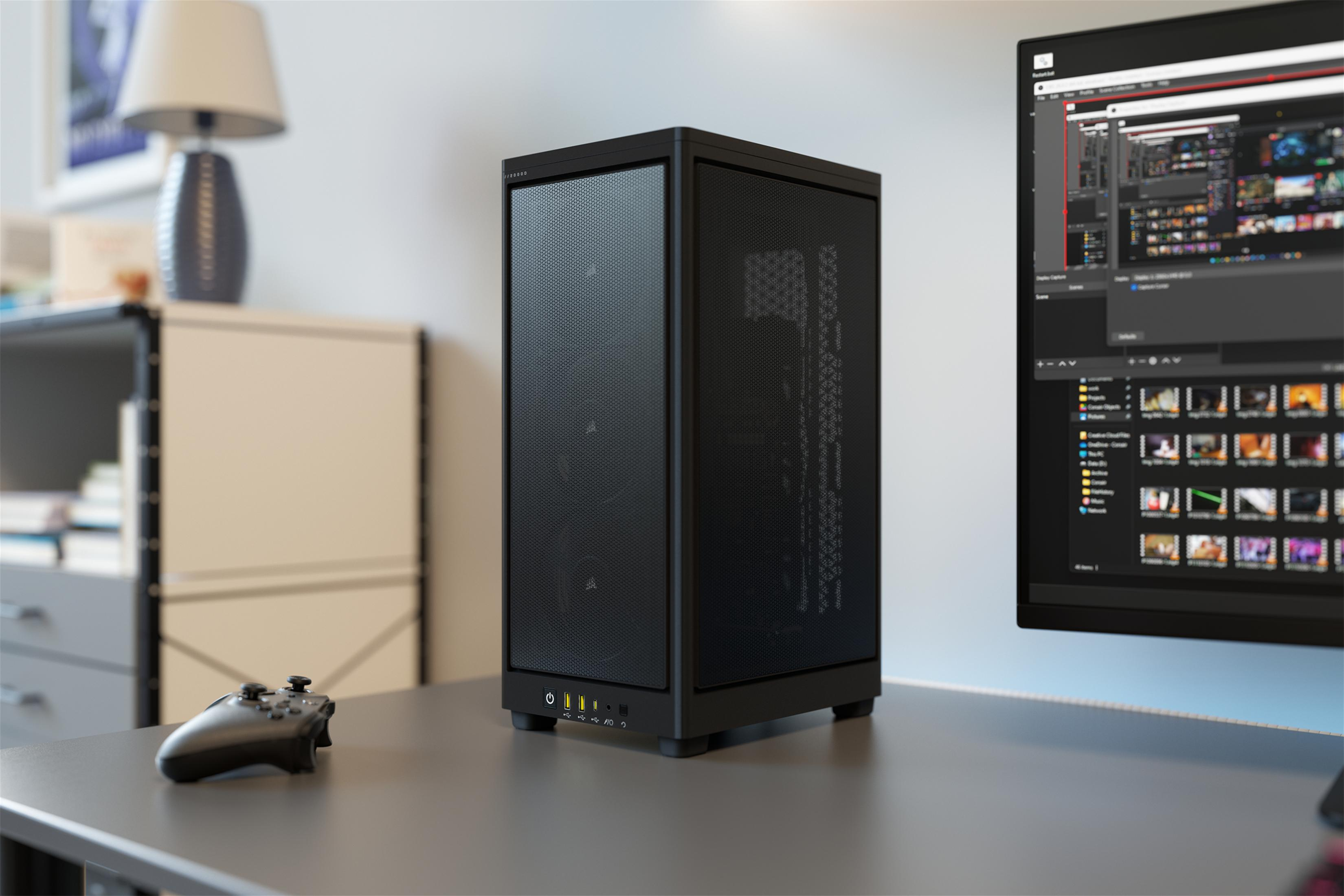 Czarna obudowa komputera na biurku z monitorem i gamepadem.