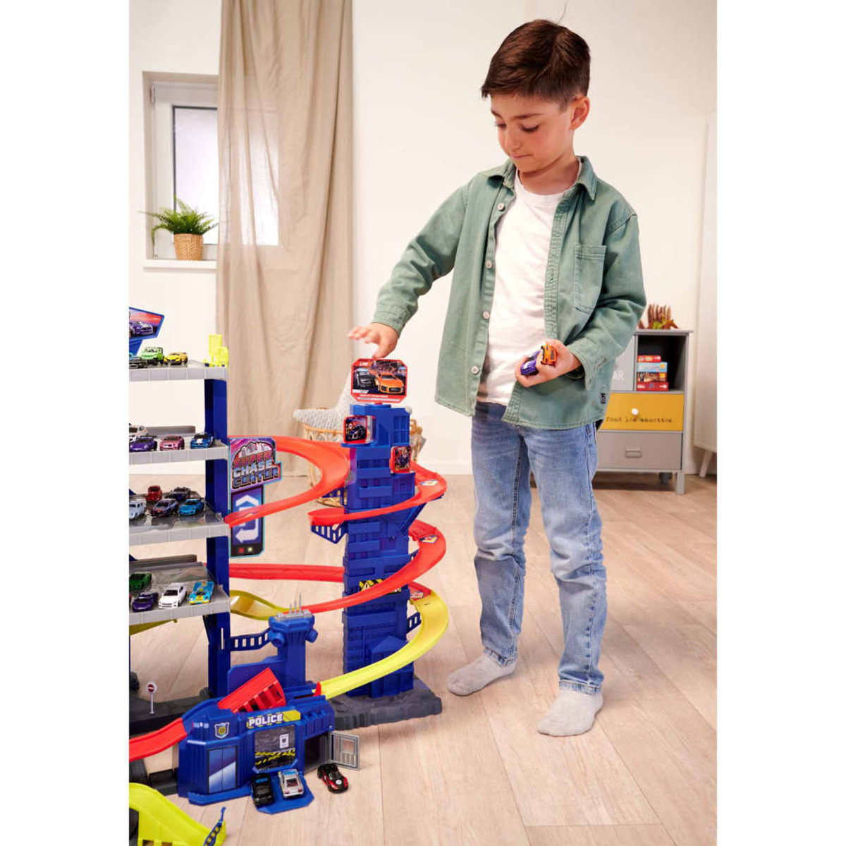 Junge spielt mit Spielzeugauto-Garage. Mehrere Spielzeugautos auf den Rampen und in den Händen.
