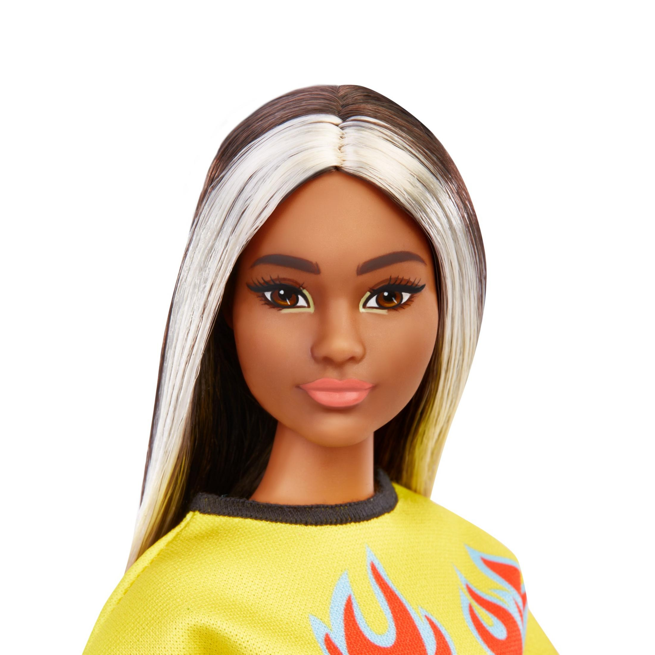 Nahaufnahme einer Barbie-Puppe. Sie hat dunkle Haut, langes schwarzes Haar mit weißen Strähnen und ein gelbes Oberteil.