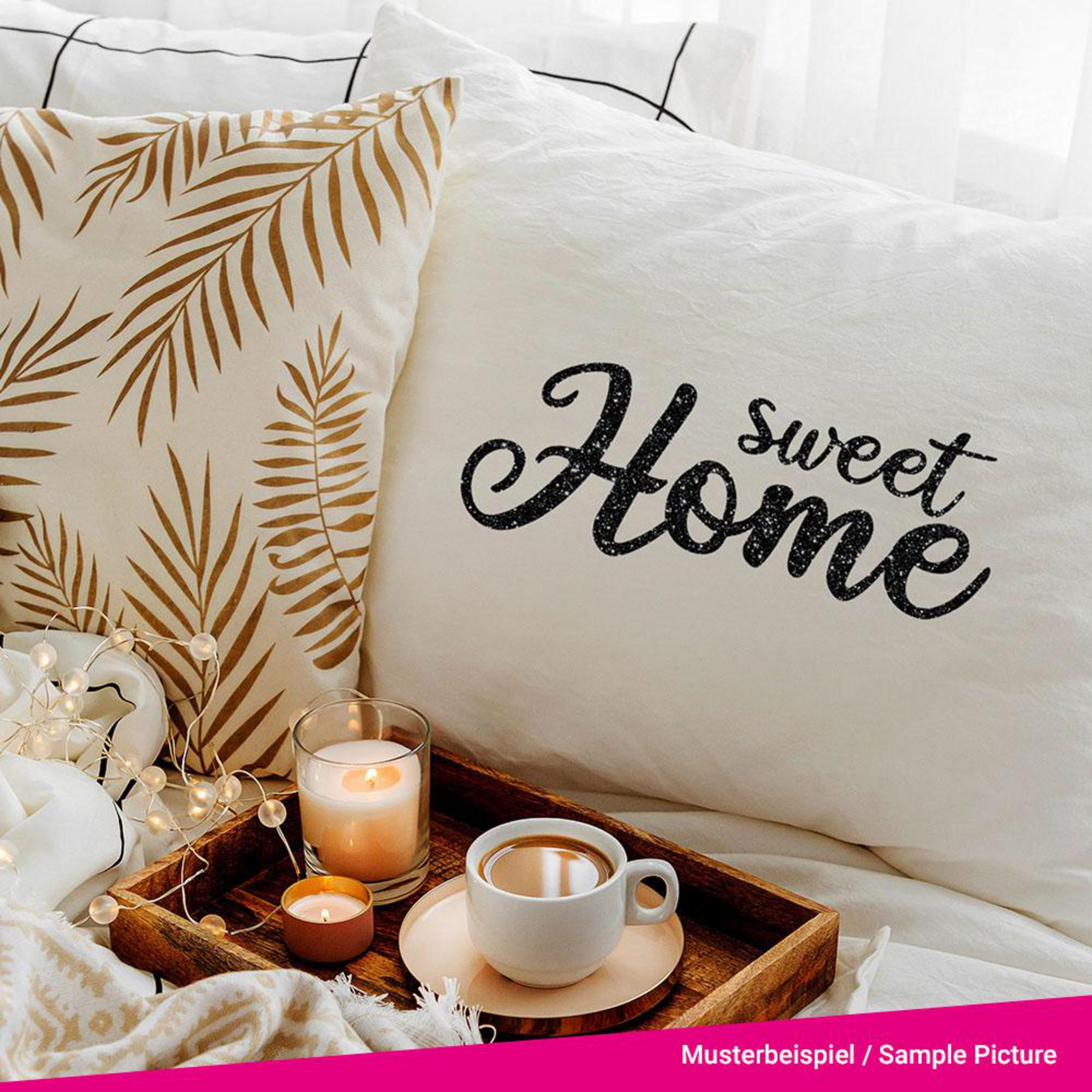 Bett mit 'Sweet Home'-Kissen, Tablett mit Kaffee, Kerze und einem Farnblatt-Kissen.
