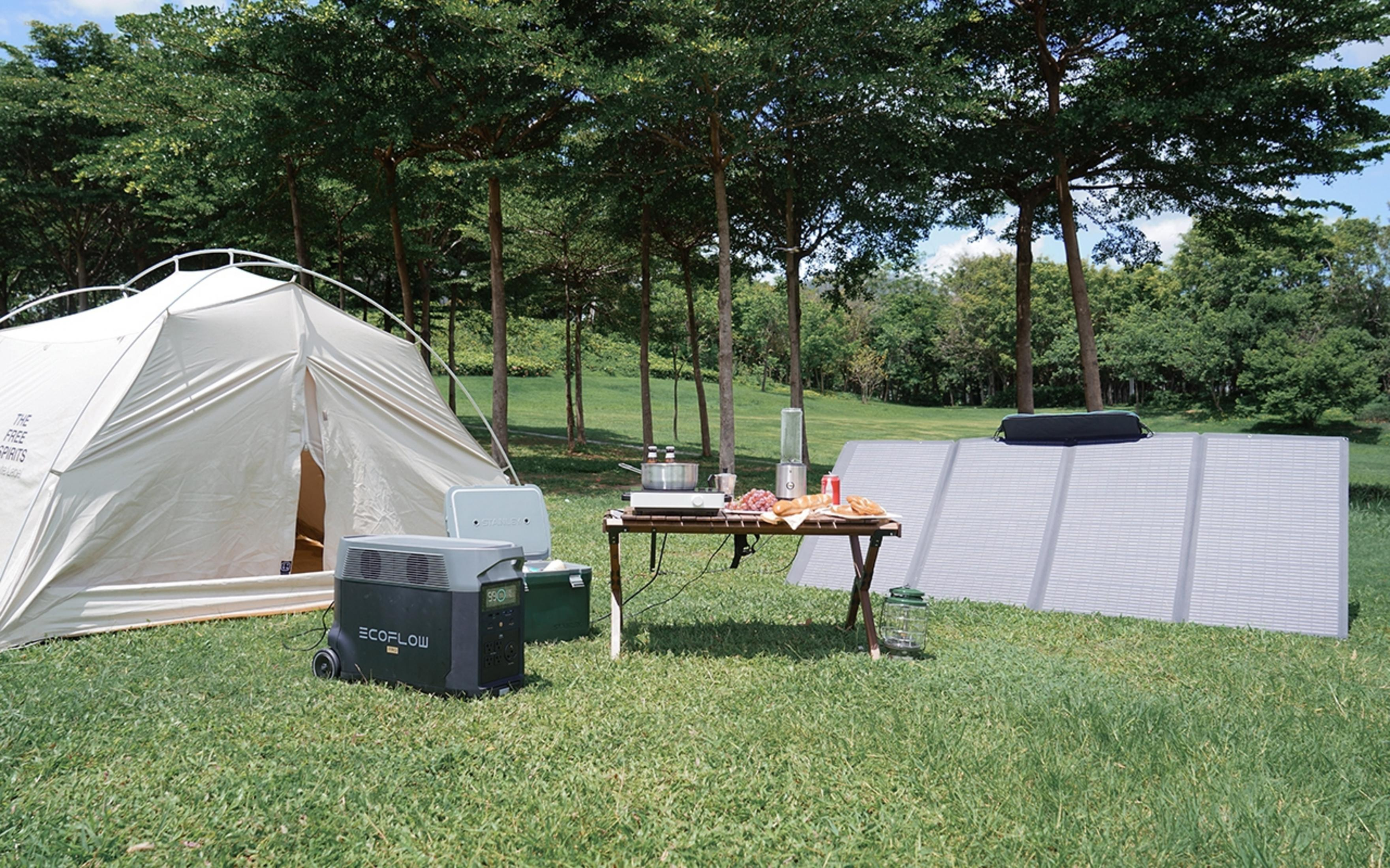 Scena kempingowa z namiotem, stołem i elektrownią w parku.