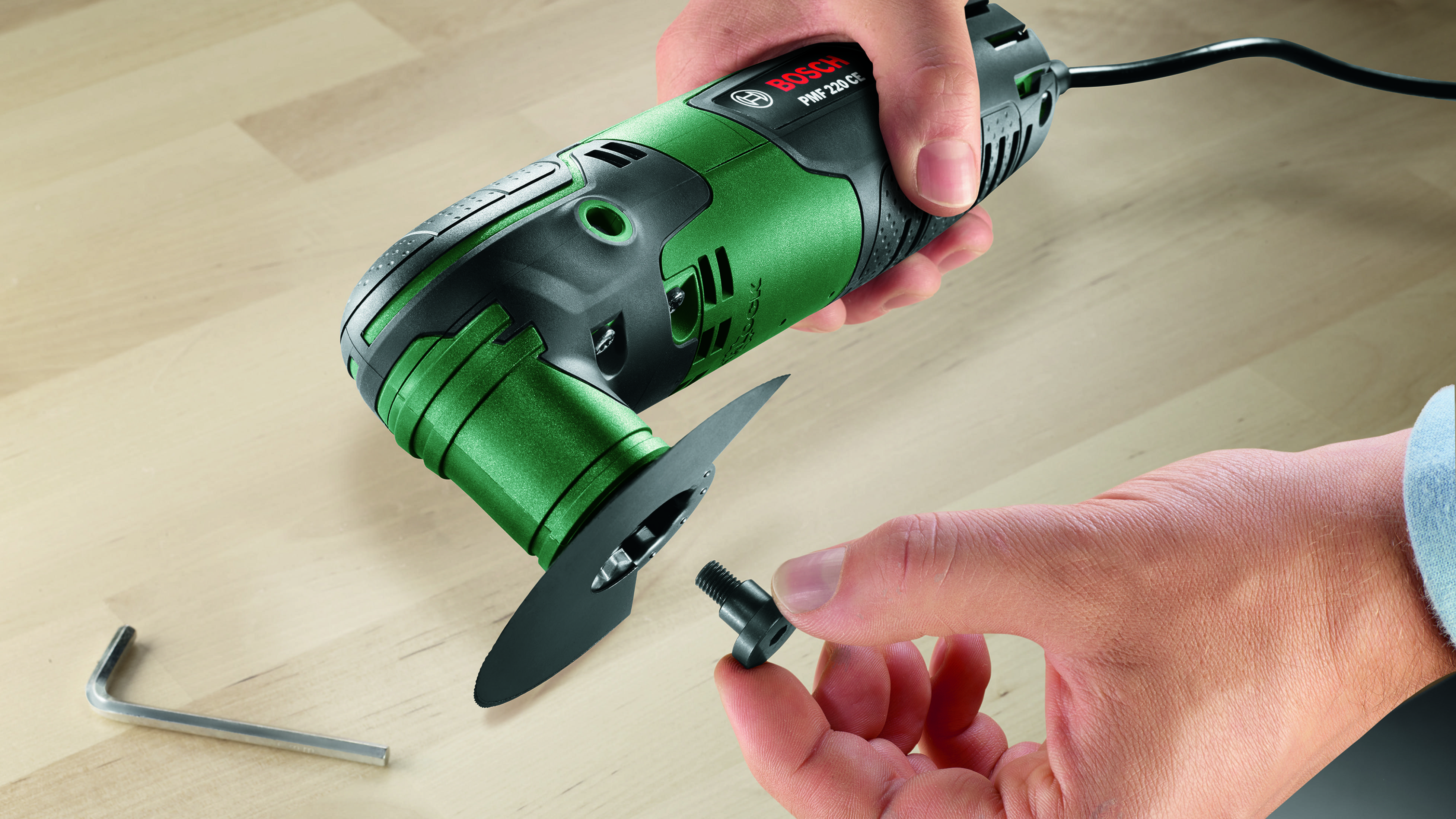 Dłonie montujące zielono-czarne elektronarzędzie ze srebrnym kluczem imbusowym.