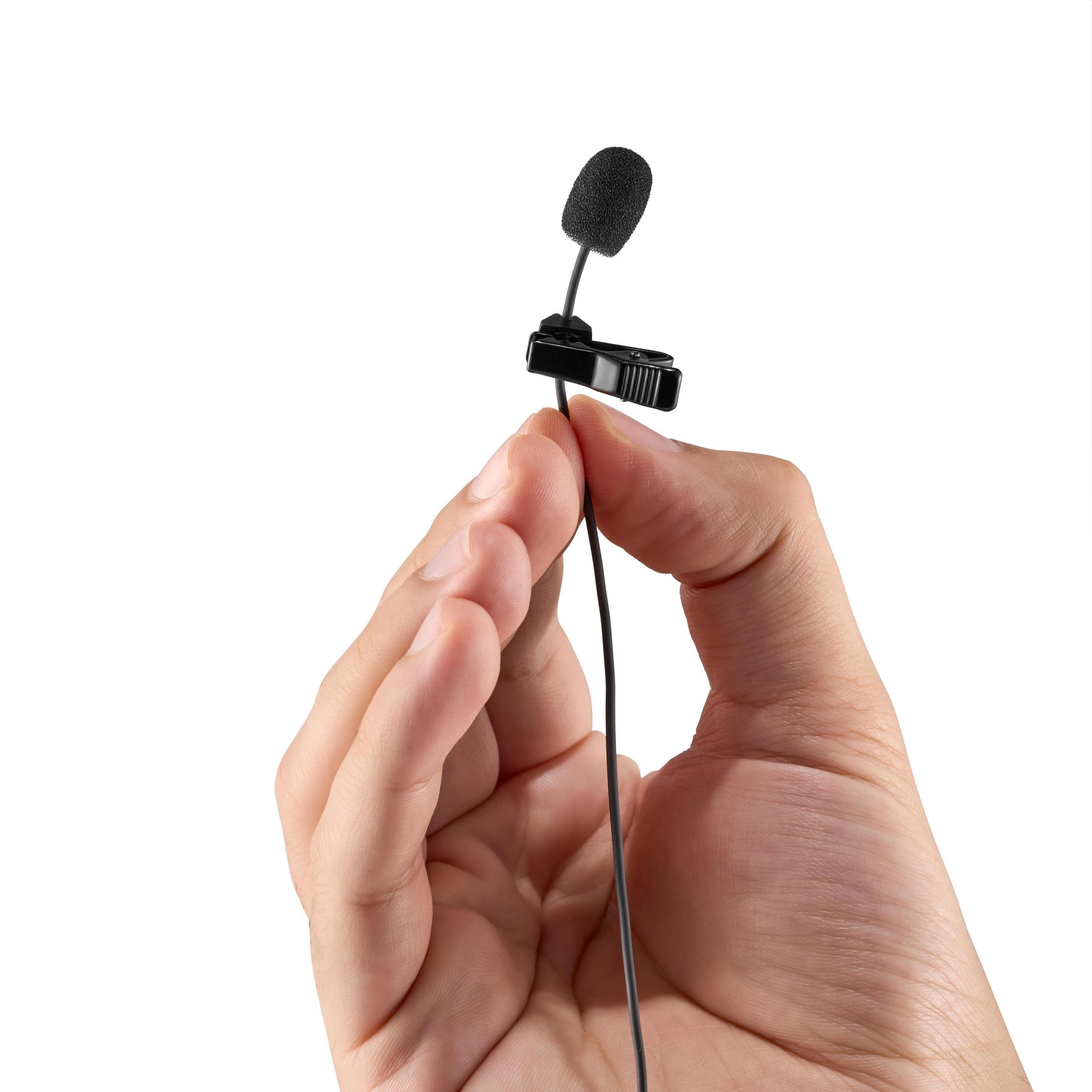 Une main tient un microphone cravate noir avec une pince noire.