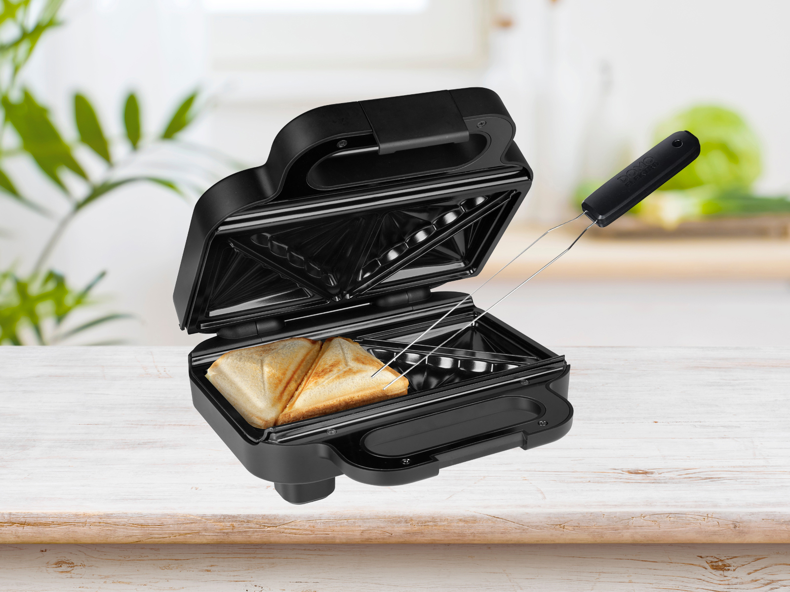 Schwarzer Sandwichmaker offen, mit zwei getoasteten Sandwiches auf Tisch.
