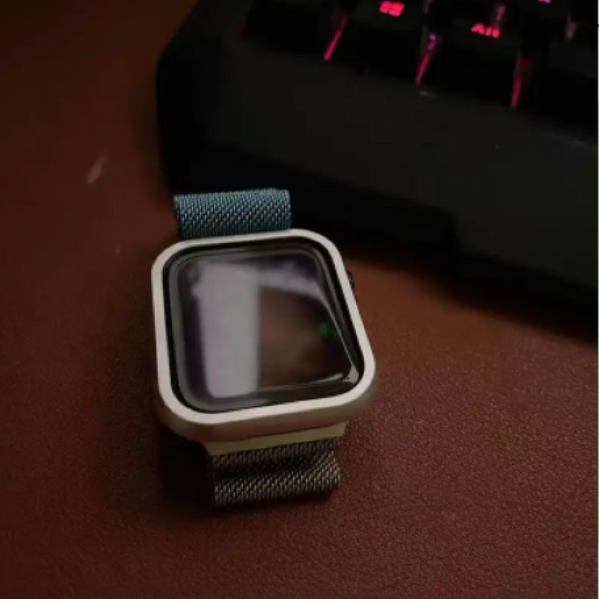 Smartwatch su una superficie marrone vicino a una tastiera nera.