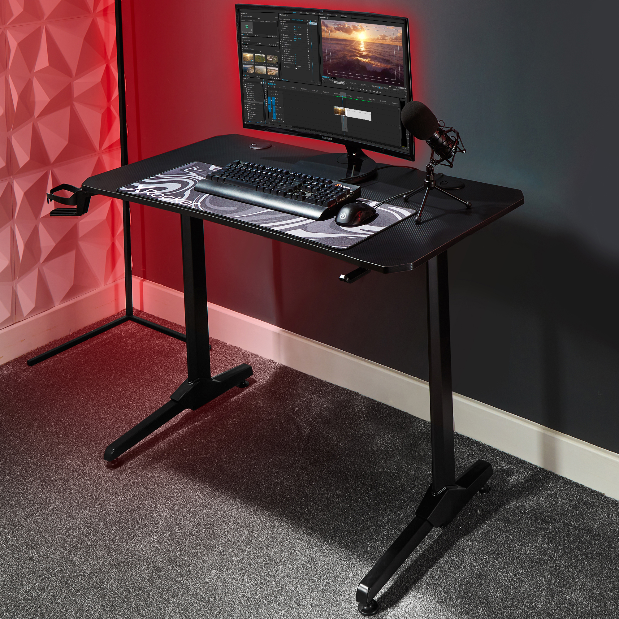 Gaming-Schreibtisch mit Monitor, Tastatur, Maus, Mikrofon und Mauspapier, mit roter Beleuchtung.