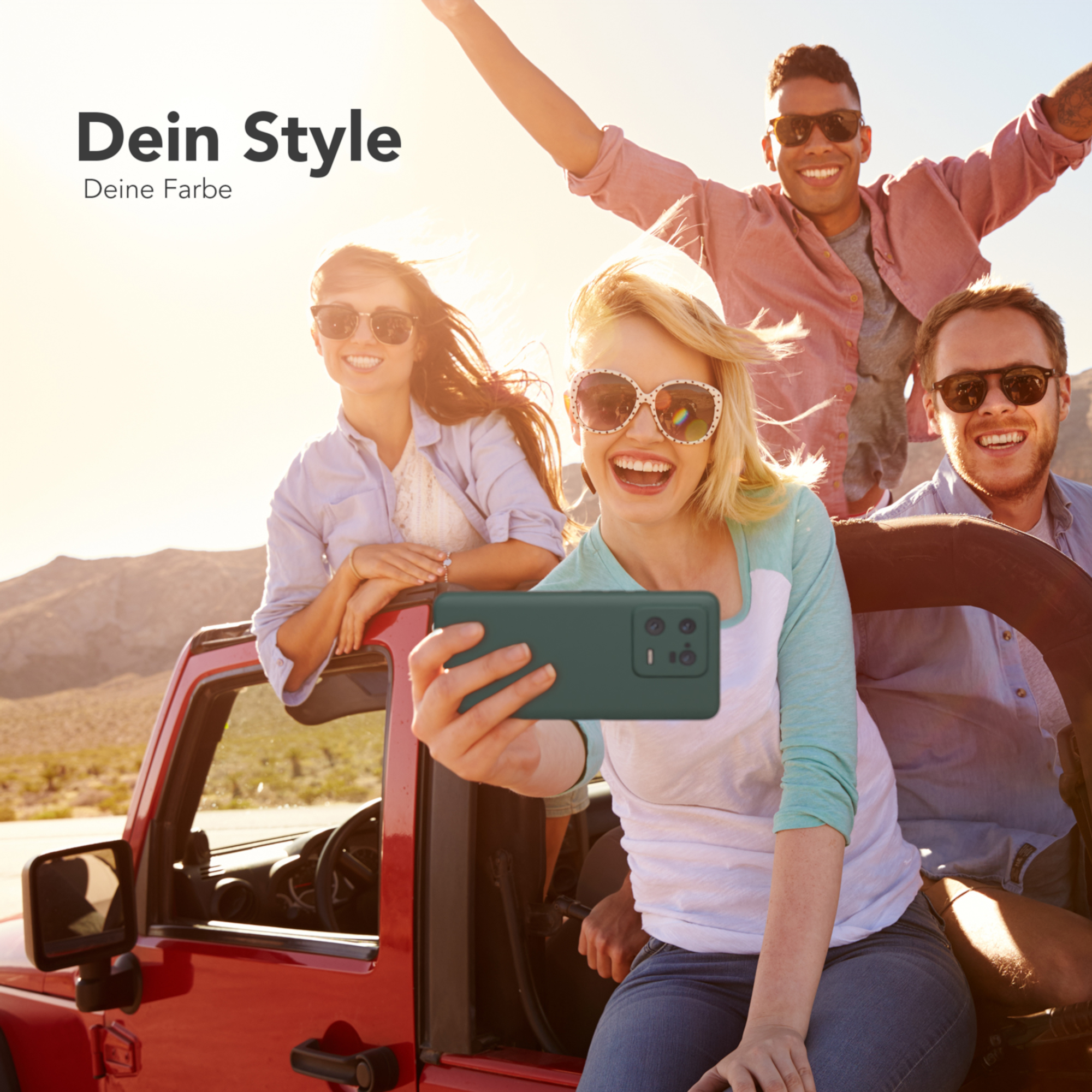 Vier Personen in einem roten Jeep machen ein Selfie. Sie lächeln und tragen Sonnenbrillen.