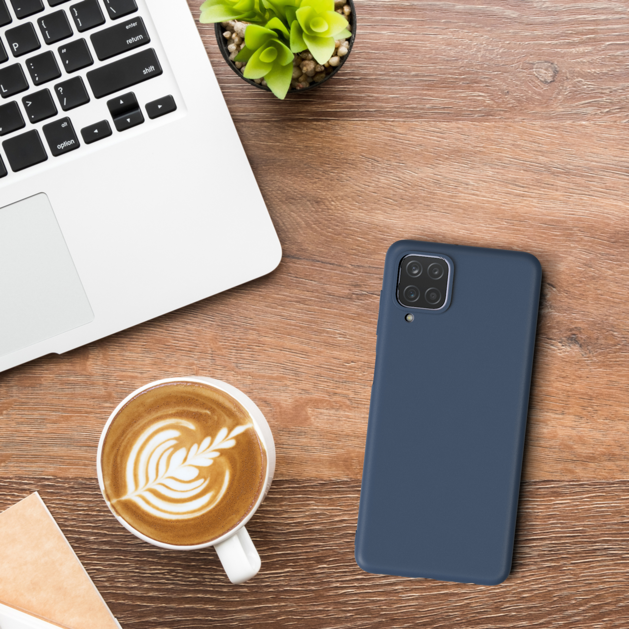 Laptop, Telefon, Kaffee und Pflanze auf einem Holzschreibtisch.