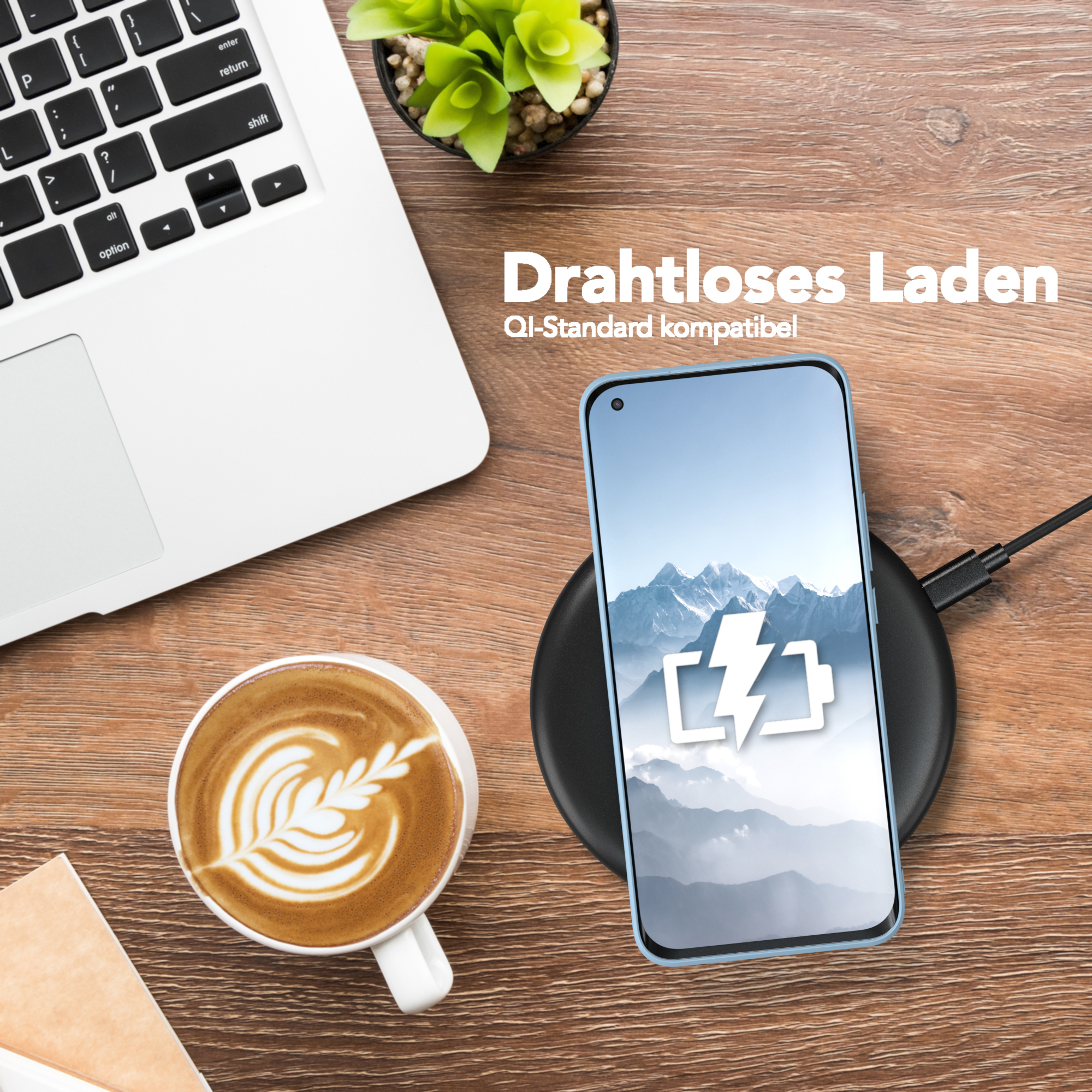 Ein Telefon, das drahtlos auf einem Pad neben einer Kaffeetasse und einem Laptop geladen wird.