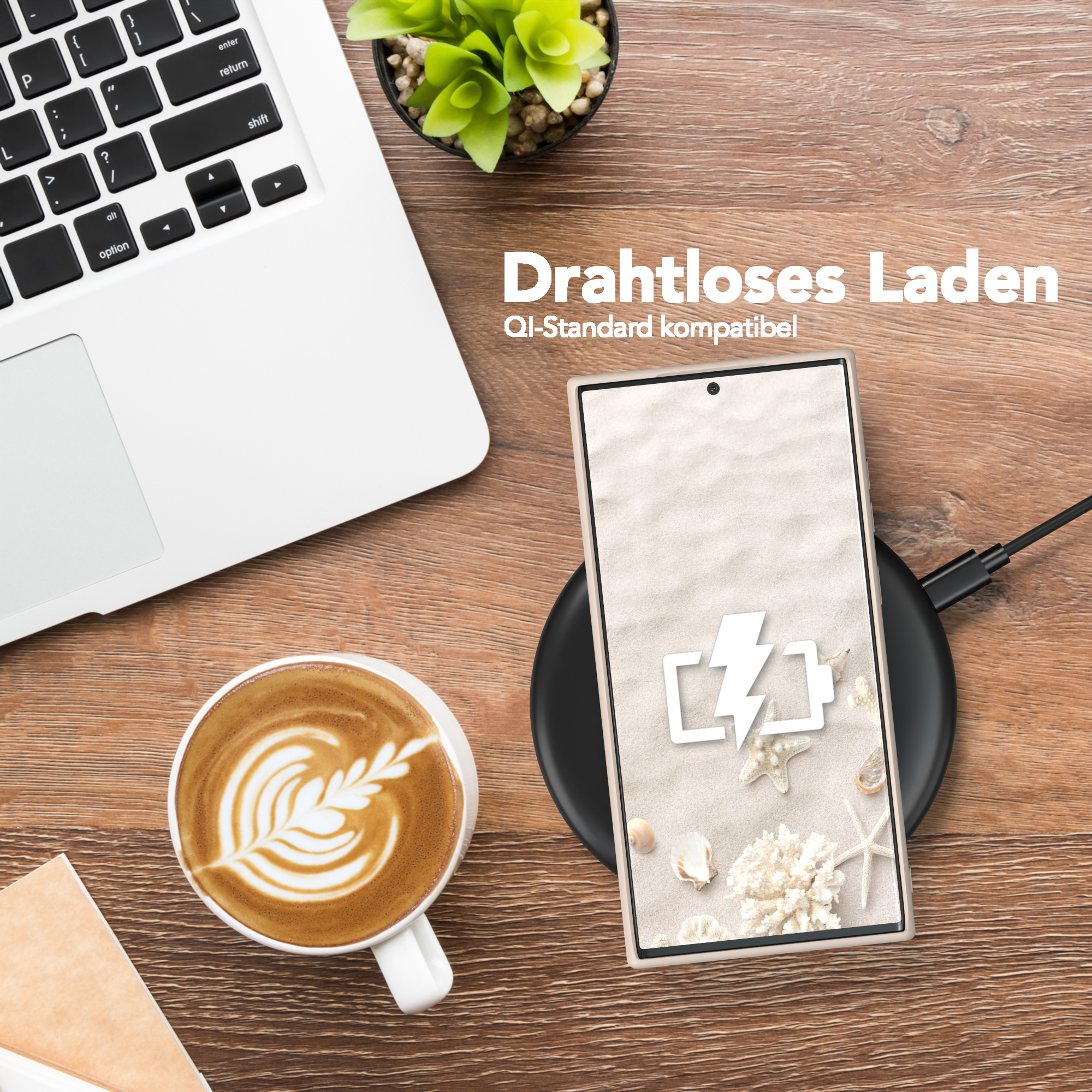 Laptop, Kaffee mit Latte Art und ein Telefon auf einem Ladepad. Telefon zeigt ein Strandbild mit Muscheln.