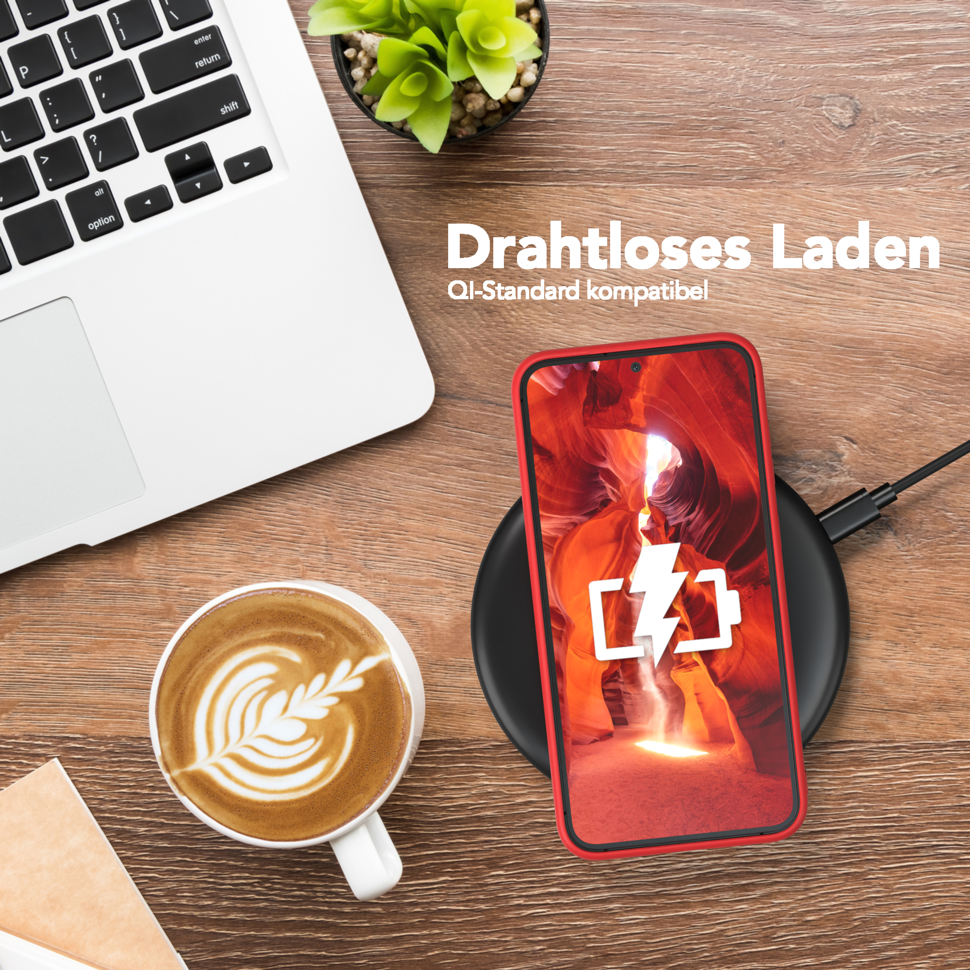 Ein Telefon lädt drahtlos neben einem Laptop und einer Kaffeetasse.