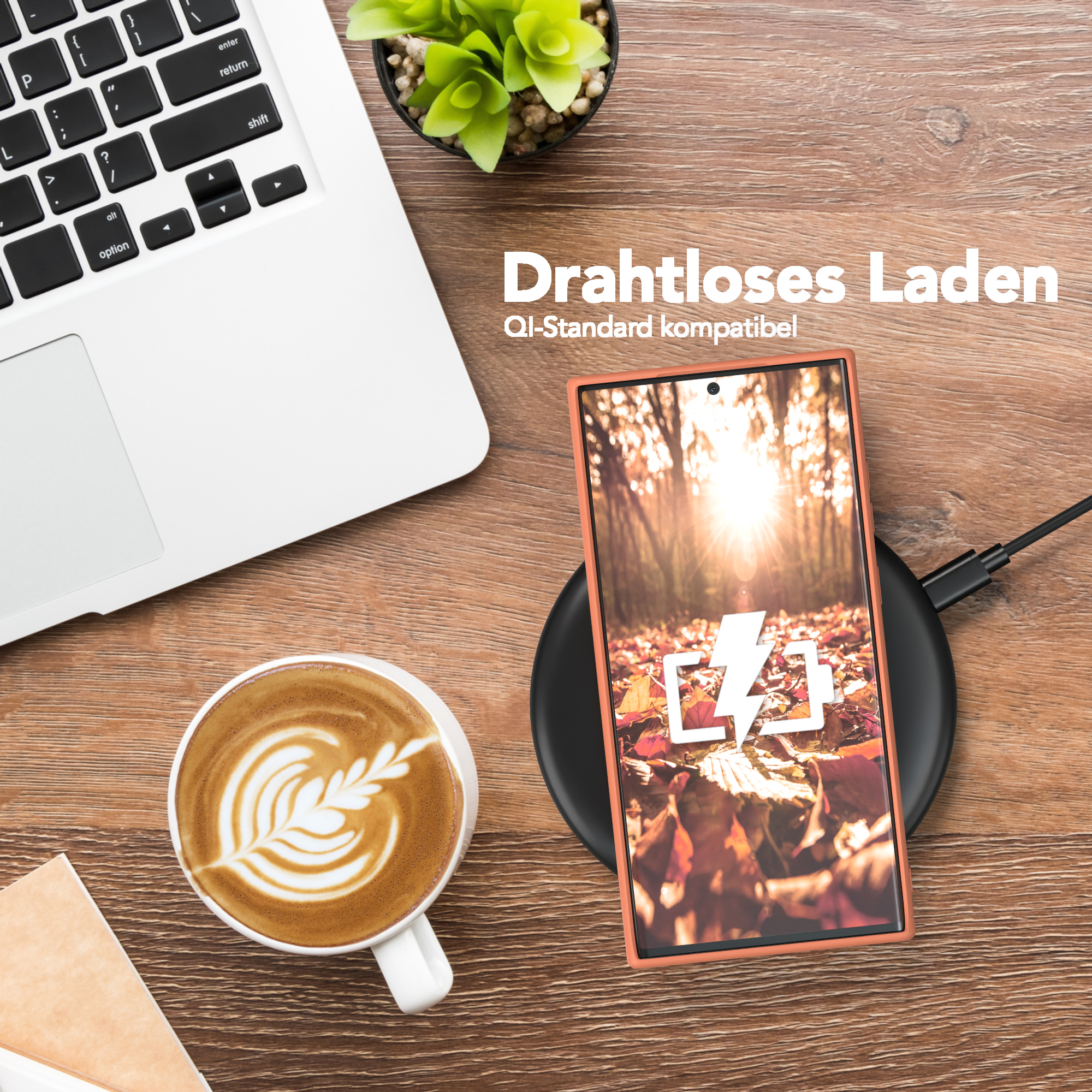Ein Telefon, das drahtlos auf einem Pad aufgeladen wird. Ein Laptop und eine Tasse Kaffee befinden sich in der Nähe auf einem Holztisch.
