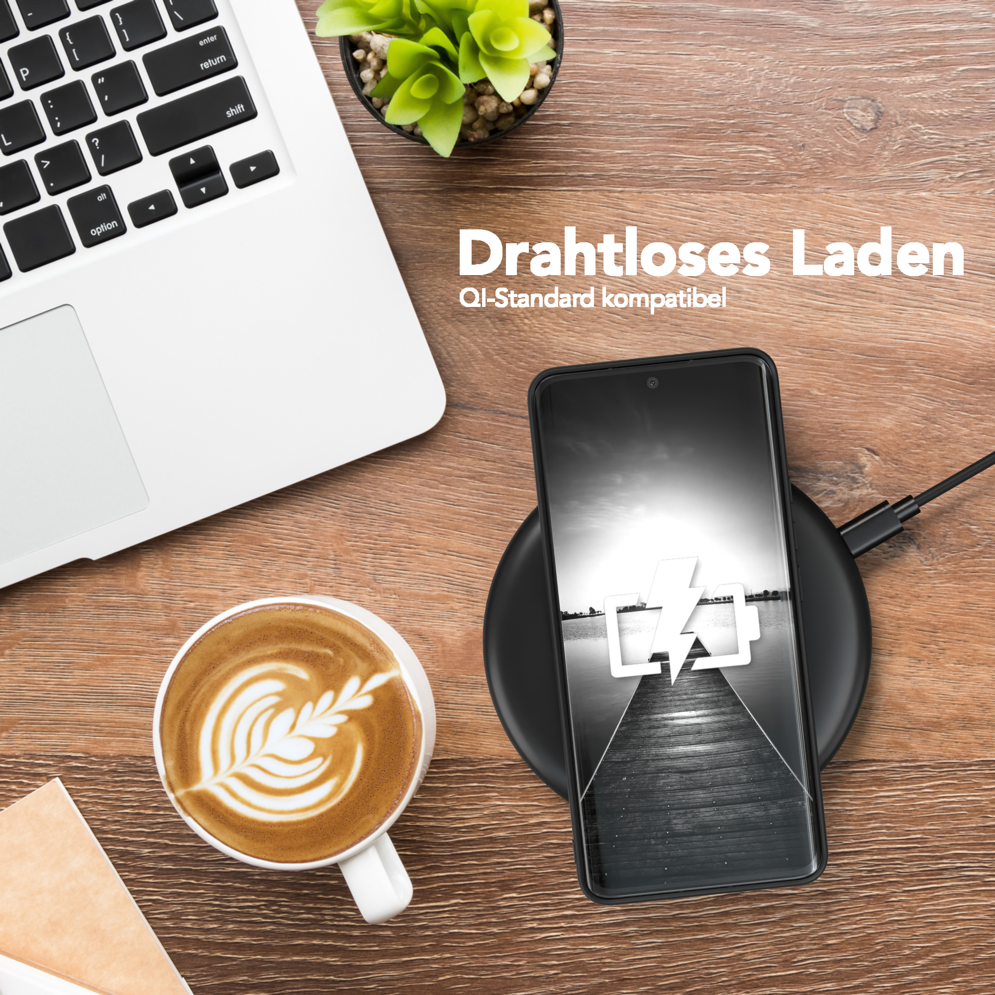Smartphone wird kabellos auf einem schwarzen Ladepad geladen, neben einem Laptop und einer Kaffeetasse.