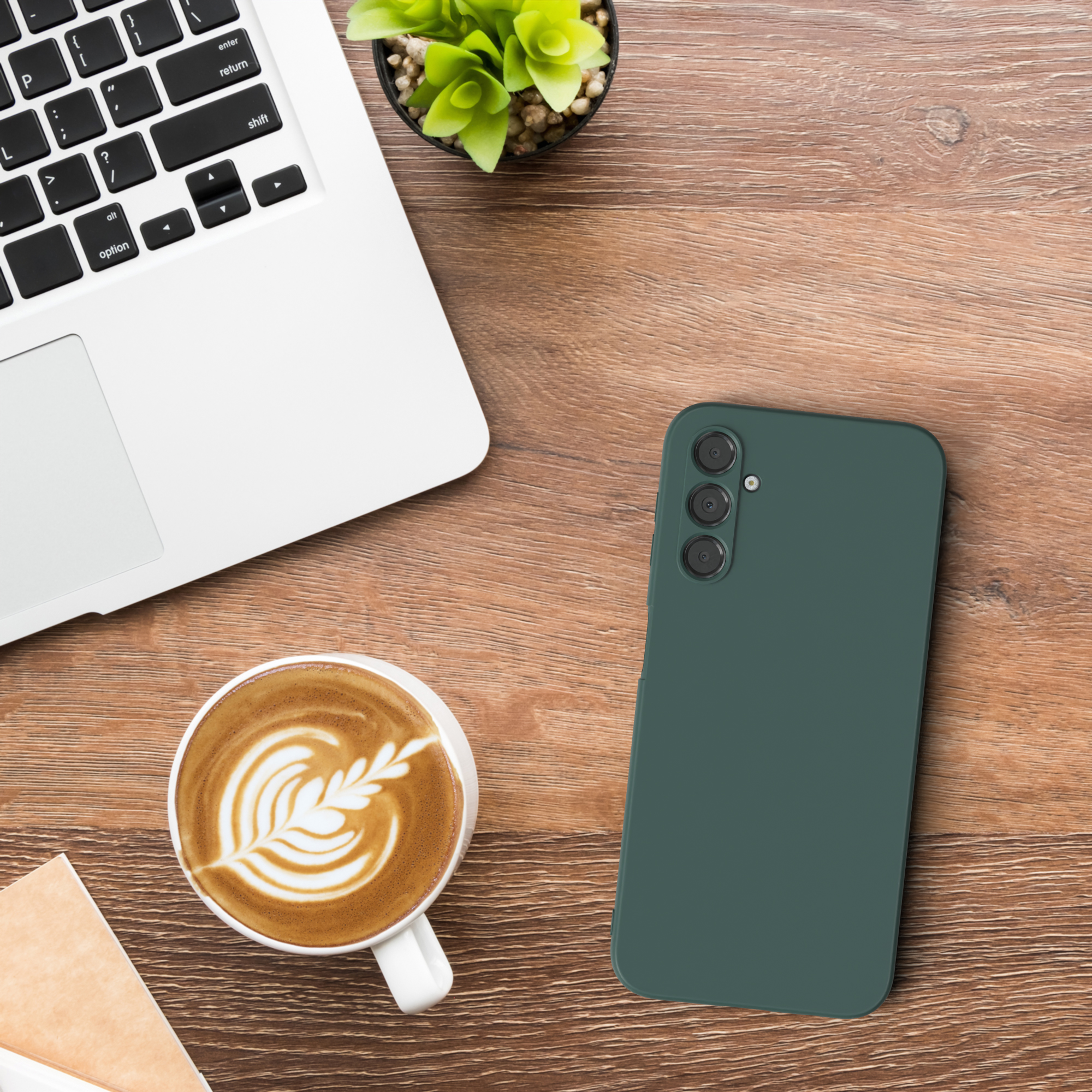 Laptop, Kaffeetasse und grünes Telefon auf einem Holzschreibtisch. Das Telefon liegt oben.