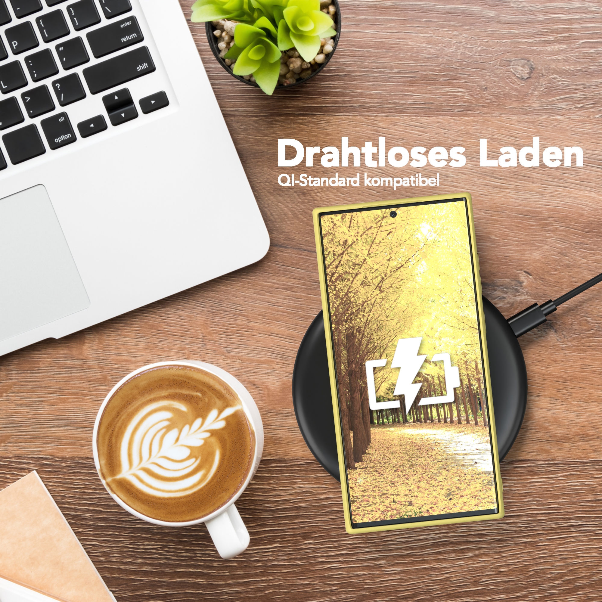 Ein Telefon wird drahtlos auf einem schwarzen Pad geladen, neben Laptop und Kaffeetasse.