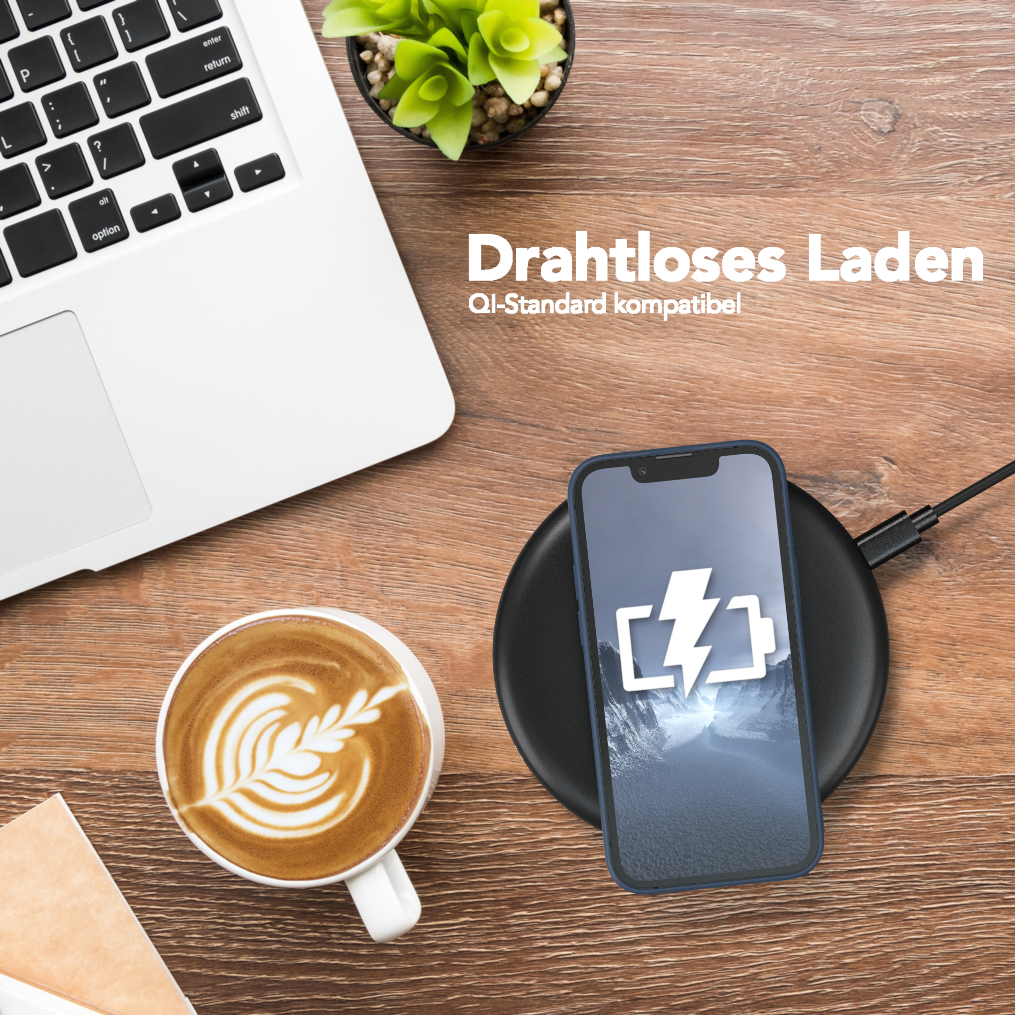 Ein Telefon lädt drahtlos neben einem Laptop und einer Kaffeetasse.