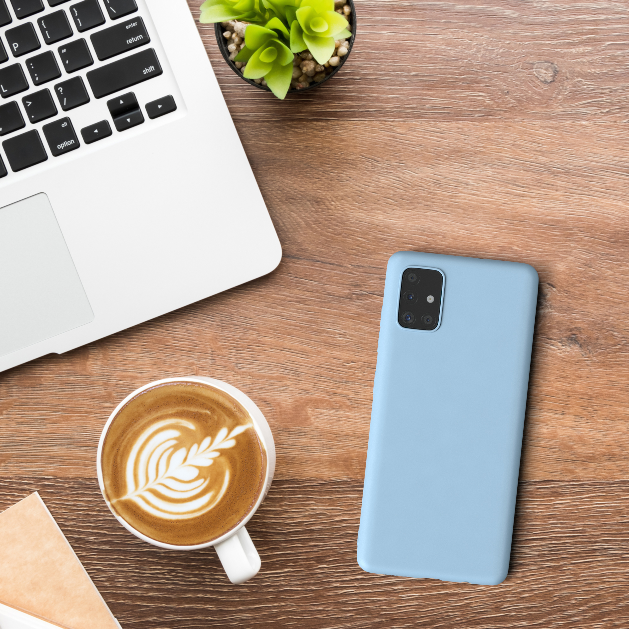 Ein Laptop, eine Kaffeetasse, ein Telefon und eine Pflanze auf einem Holztisch.