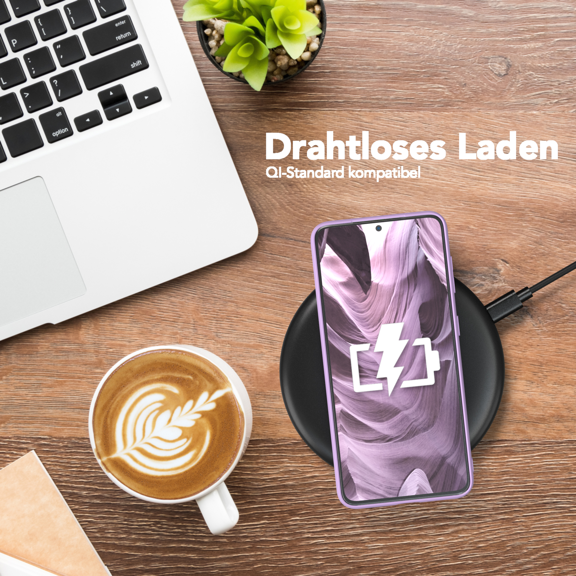Ein Laptop, eine Kaffeetasse mit Latte Art, ein Telefon auf einem kabellosen Ladegerät und eine grüne Pflanze.