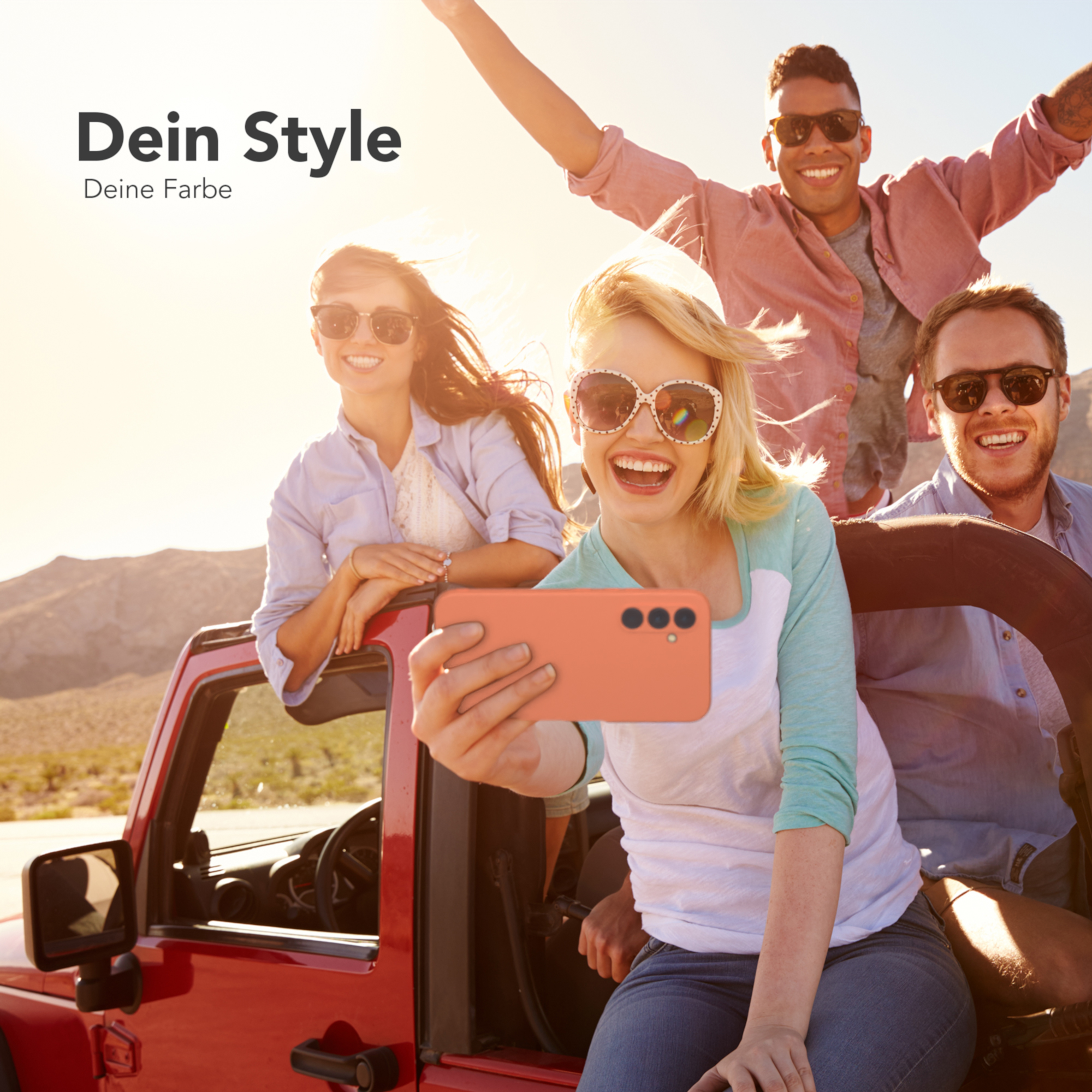 Vier Personen machen ein Selfie in einem roten Auto. Sie lächeln und tragen Sonnenbrillen, in einer sonnigen Umgebung.