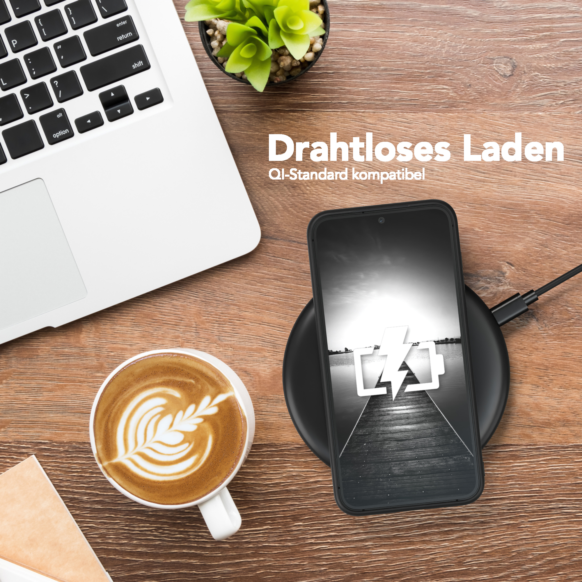 Ein Telefon, das auf einem kabellosen Ladegerät geladen wird. Ein Laptop und eine Kaffeetasse auf dem Tisch.