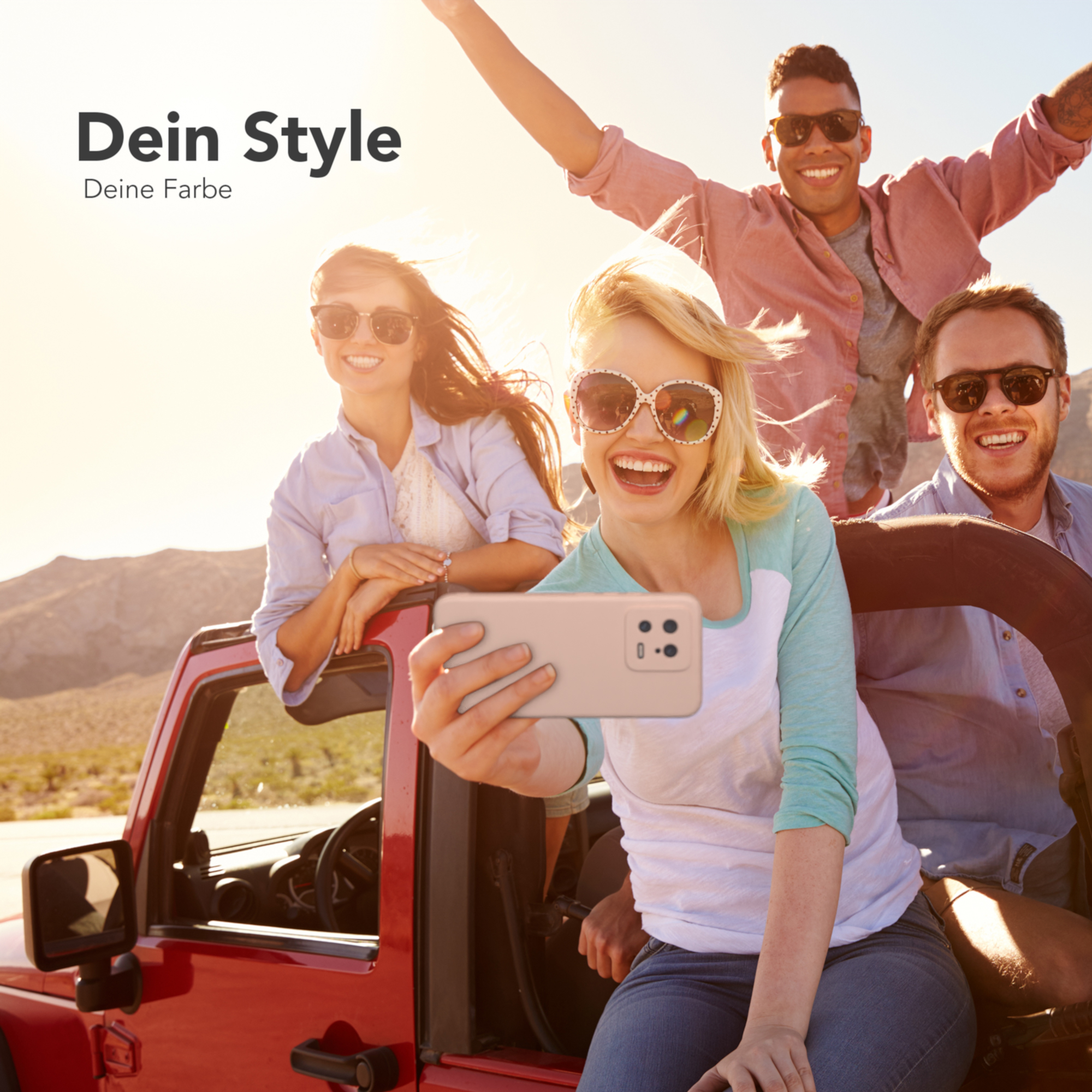 Vier Personen in einem roten Jeep, die ein Selfie mit einem Telefon machen, lächeln in der Sonne.