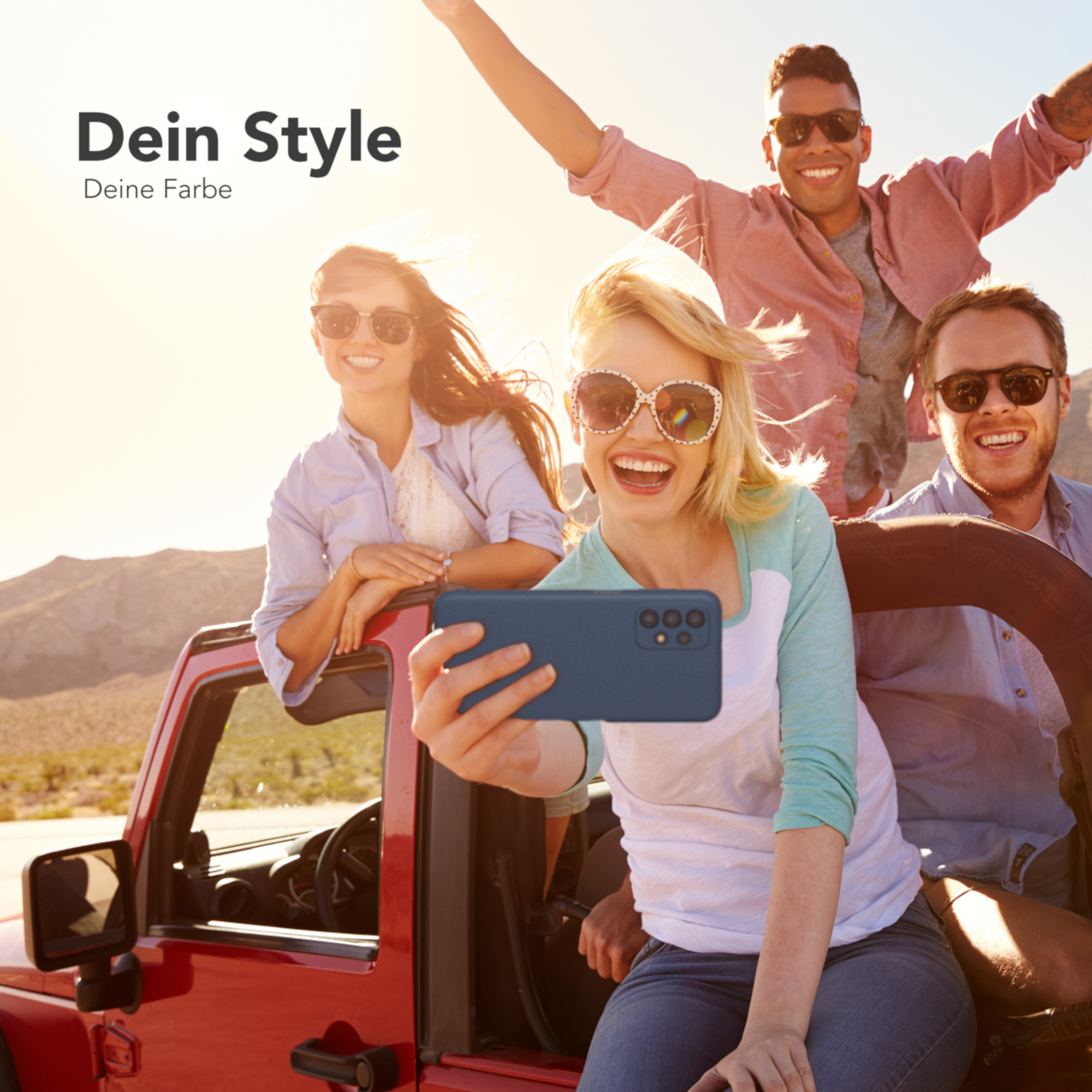 Leute in einem roten Jeep machen ein Selfie. Sonniger Tag, Berge im Hintergrund.