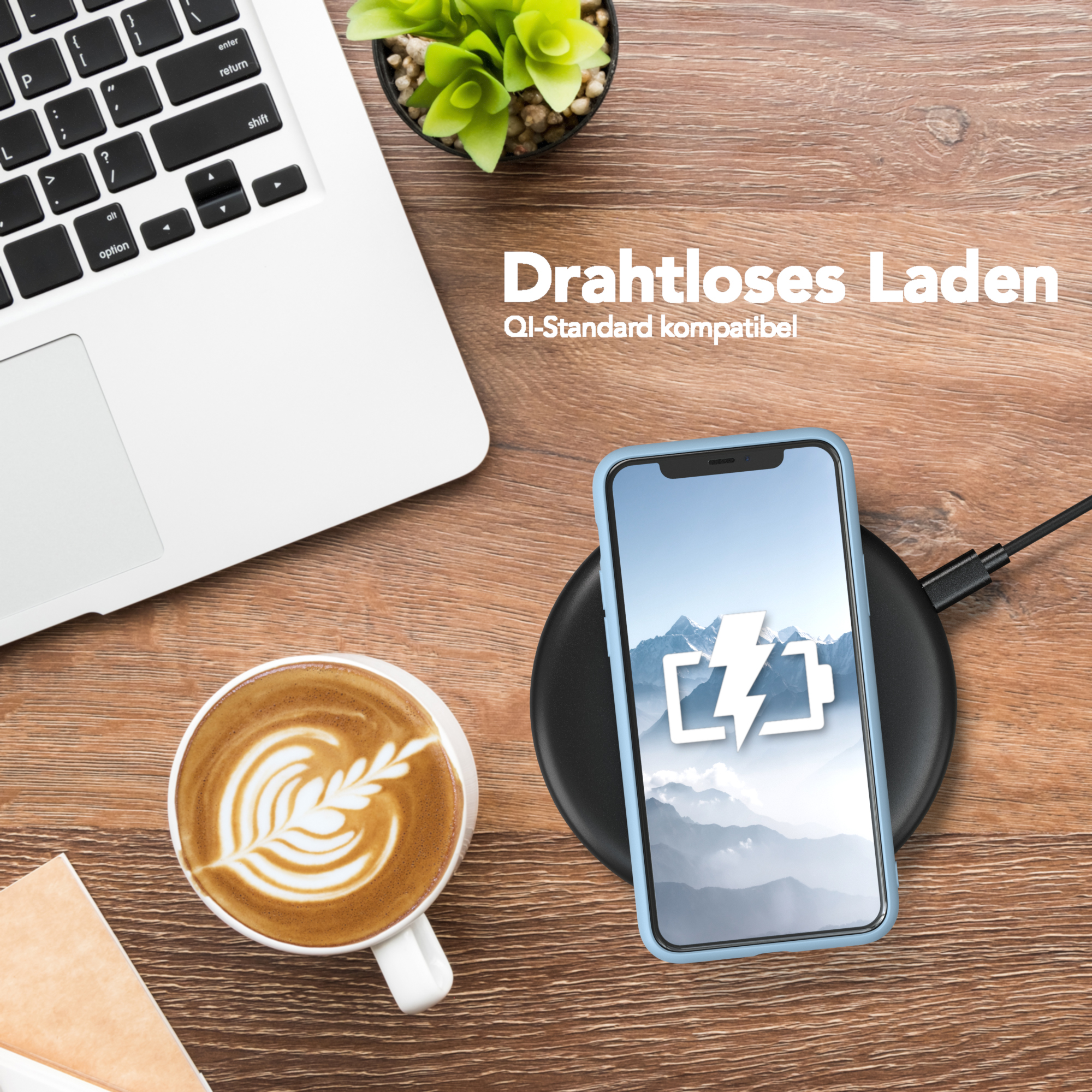 Telefon mit blauer Hülle auf Ladepad, neben Laptop und Kaffeetasse. Holzschreibtischoberfläche.