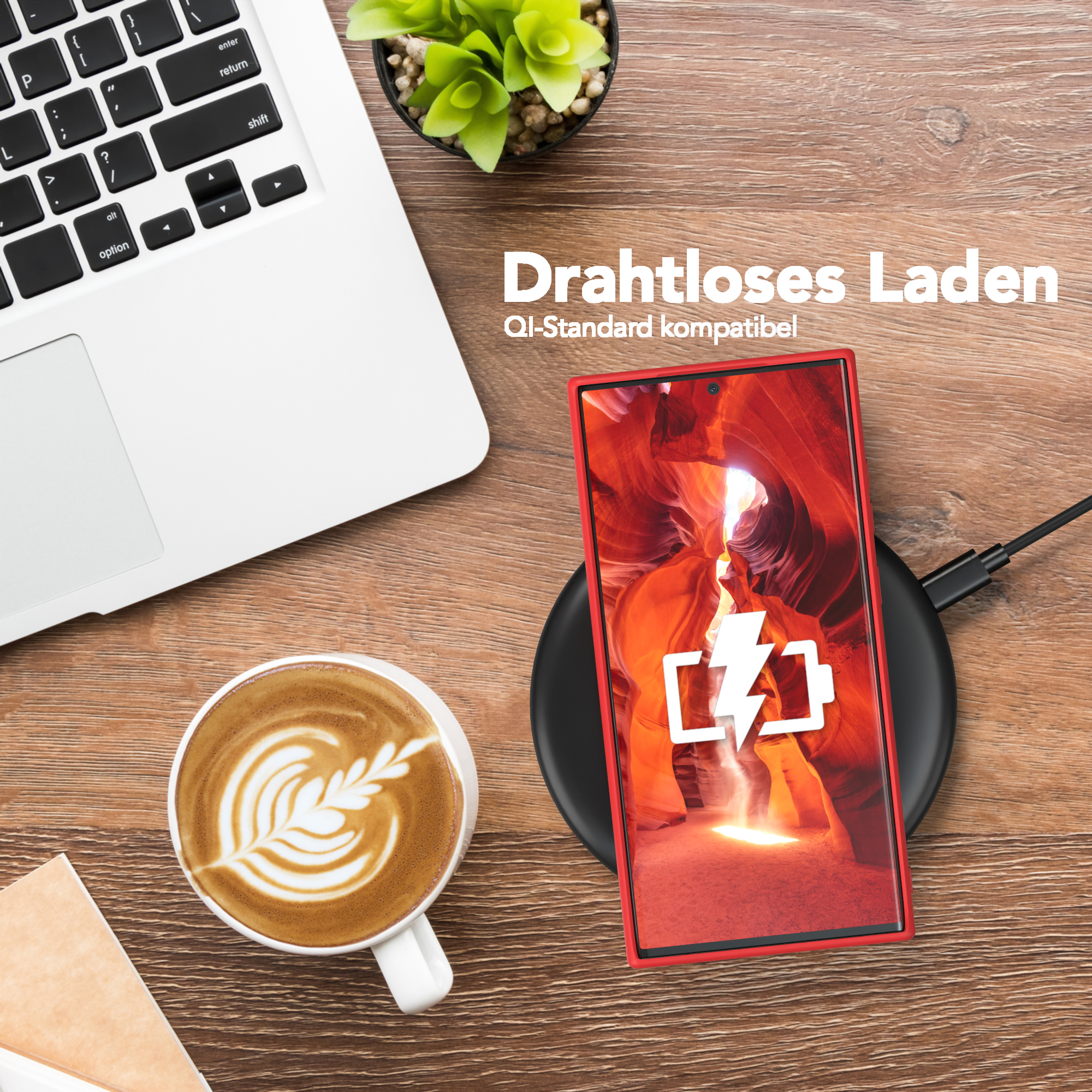 Telefon mit roter Hülle auf kabellosem Ladegerät, neben einem Laptop und einer Kaffeetasse.